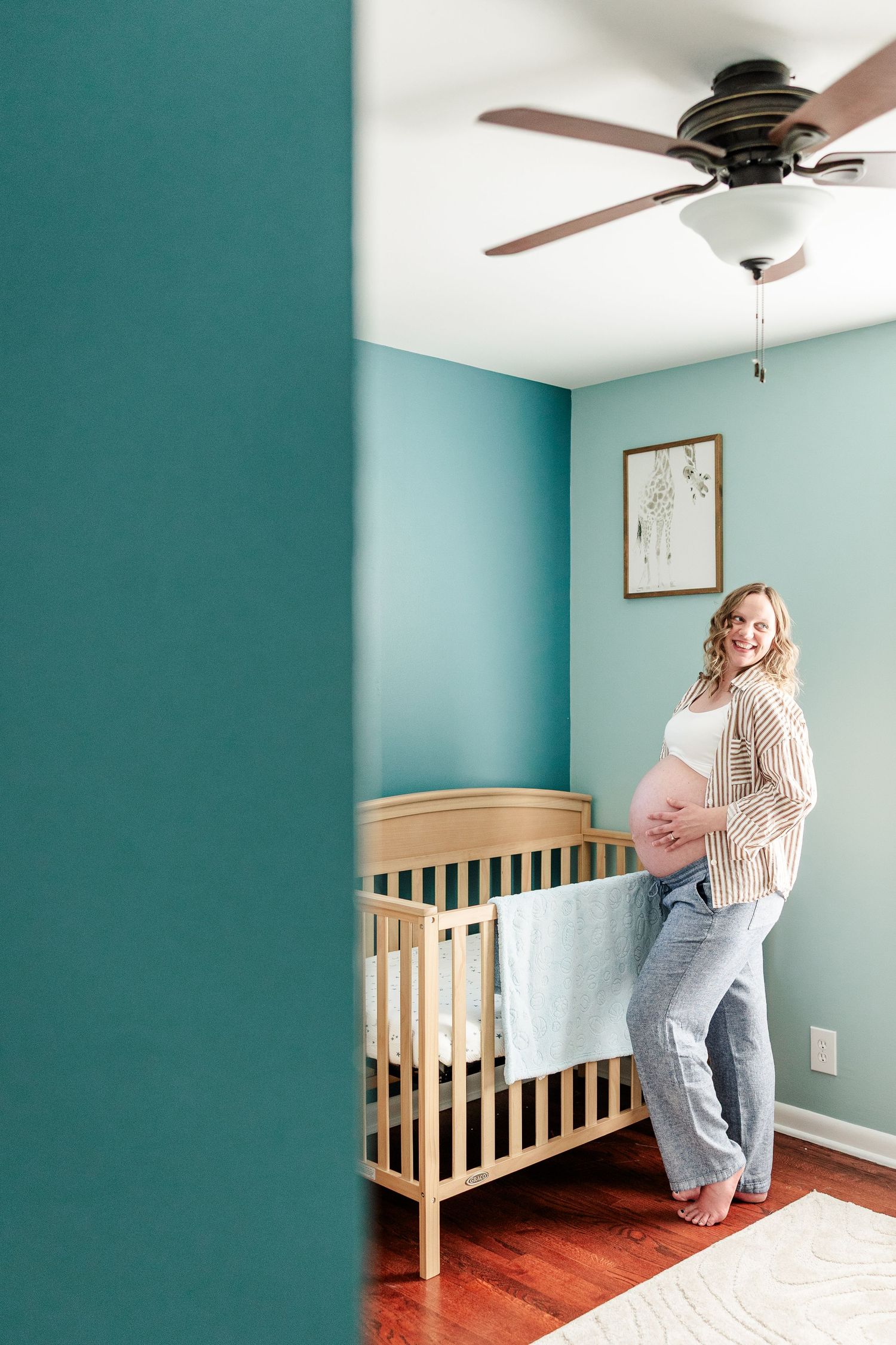 Maternity portrait beside twin nursery cribs during an in-home maternity session in Crystal Lake, Illinois.
