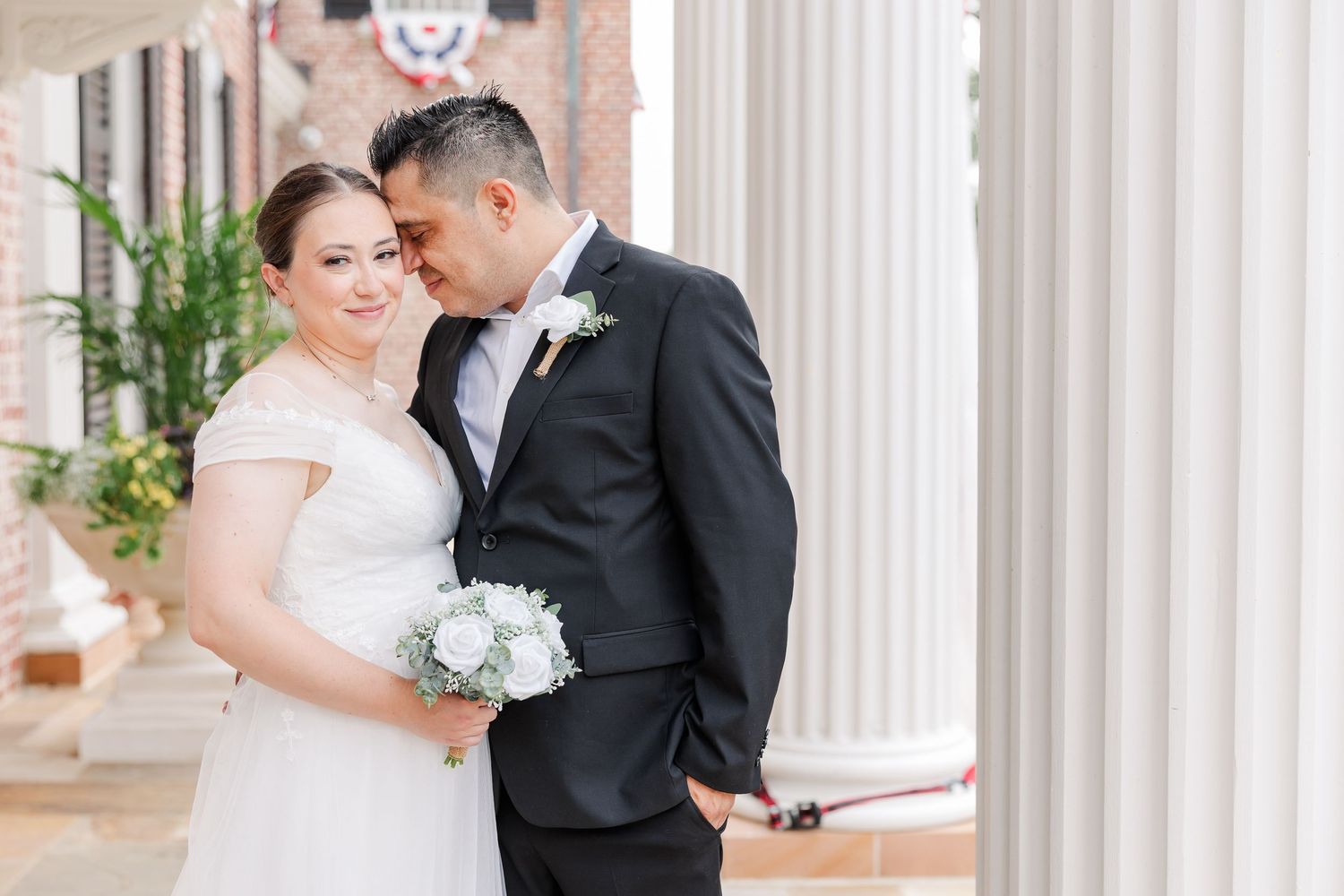 Bride and groom sharing a quiet moment beneath the columns at McCormick House in Cantigny Park.