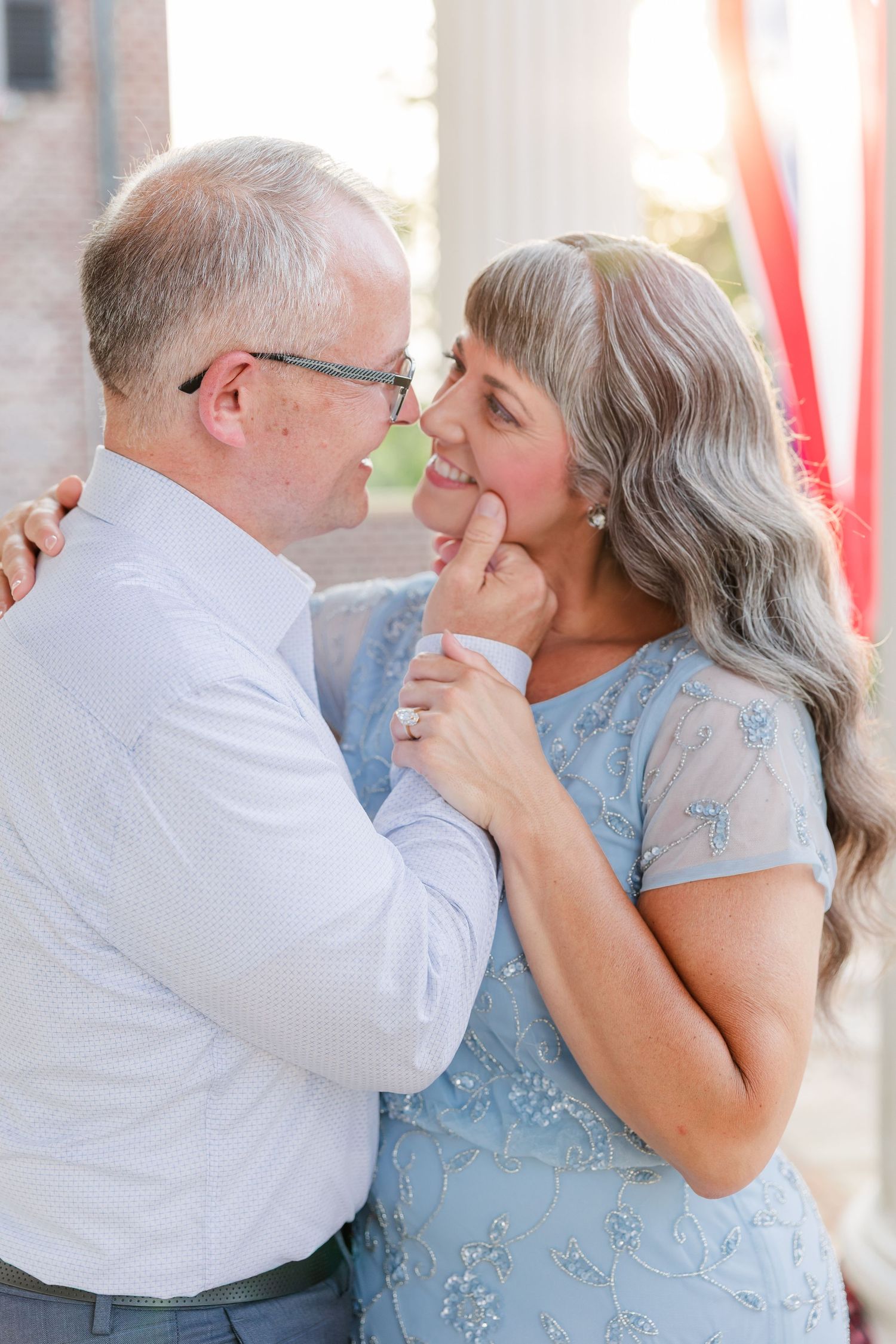 Mature couple sharing a tender moment, man gently holding womans chin, both smiling warmly at each other.