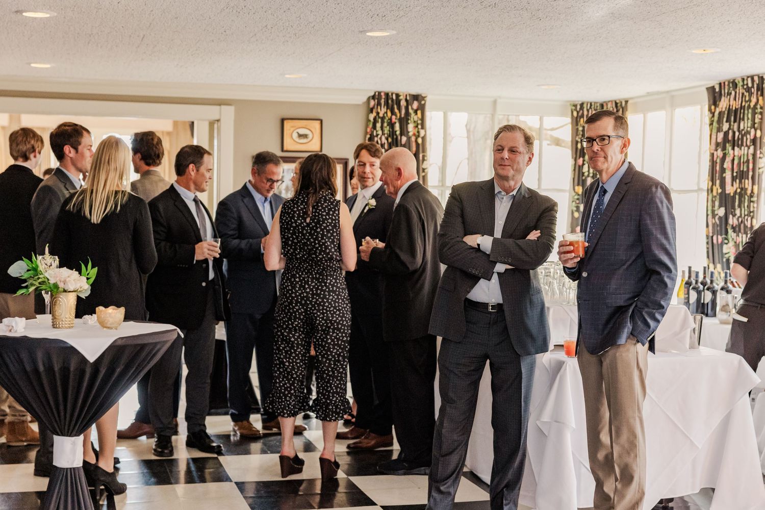 Group of formally dressed guests mingling at an elegant indoor reception.