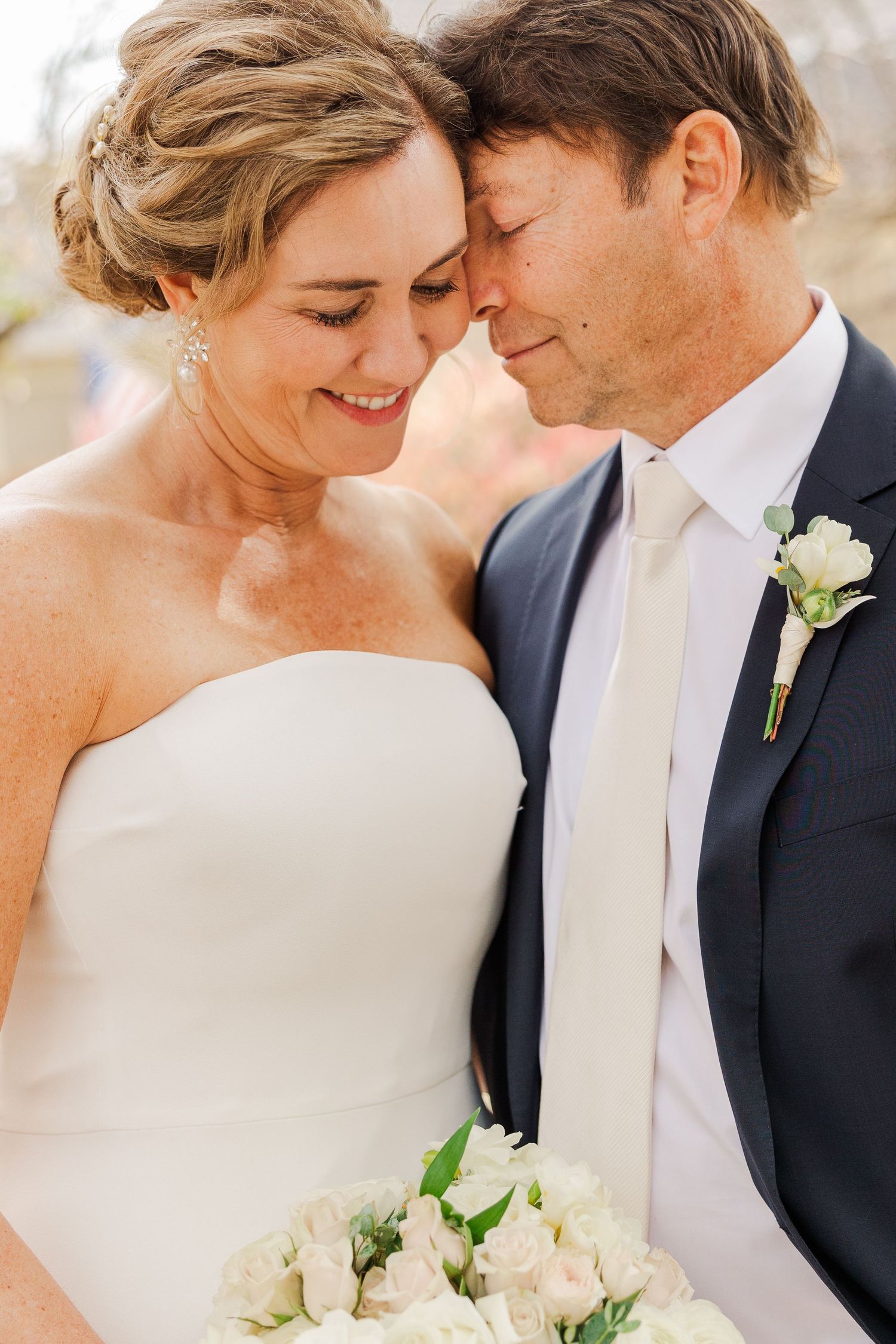 A close-up wedding portrait capturing a tender moment with white roses.