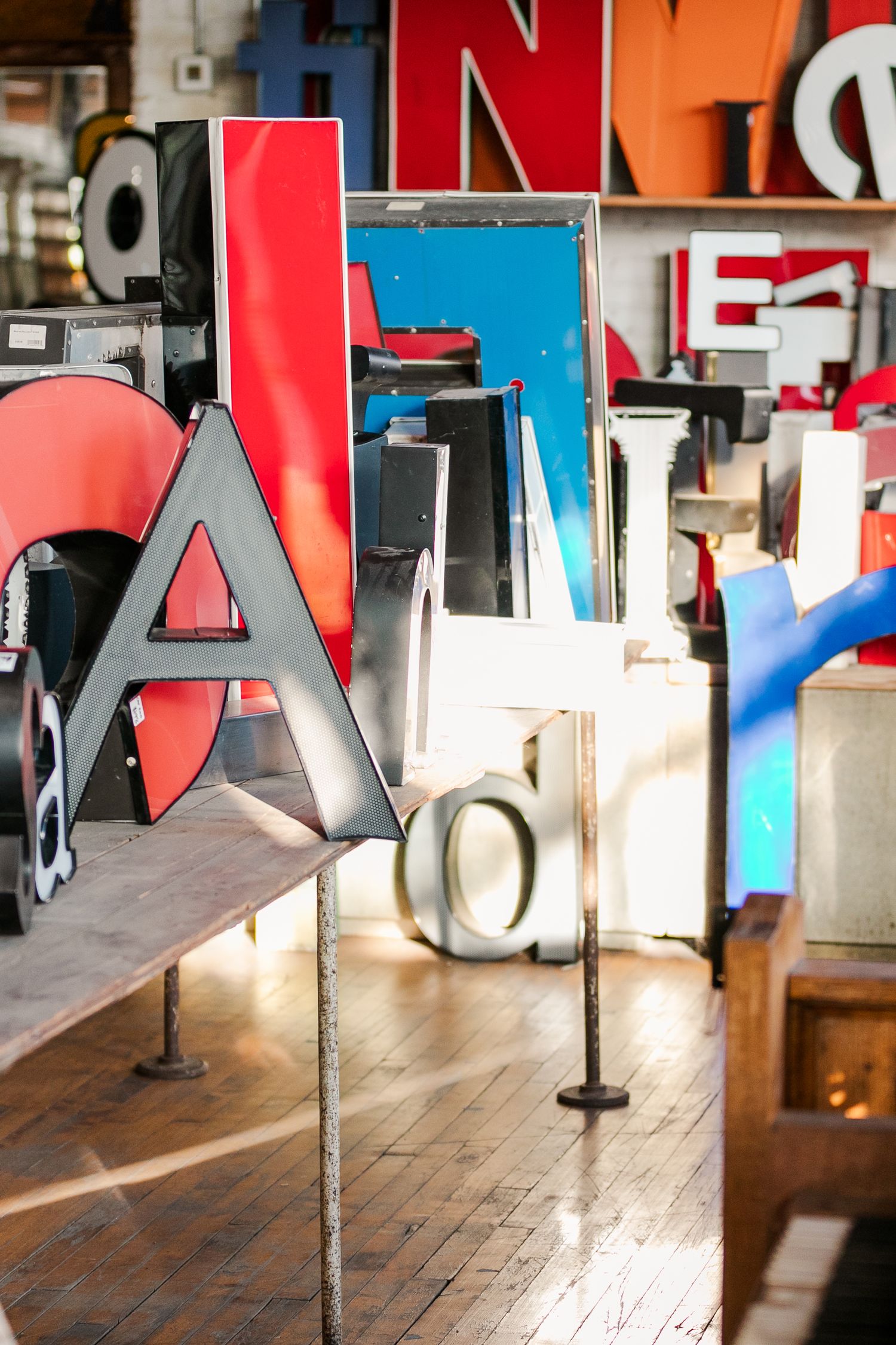 Colorful vintage letters and signage displayed on wooden floors in an industrial space.