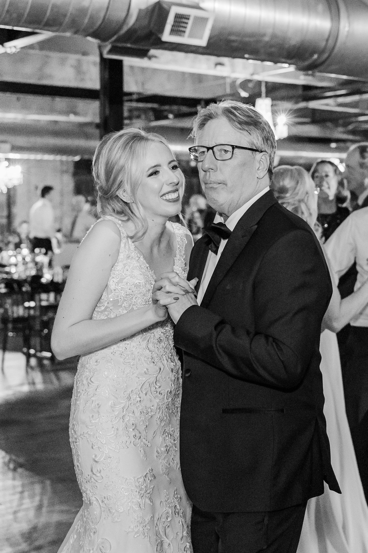 A tender black and white dance moment in an industrial-style reception space.