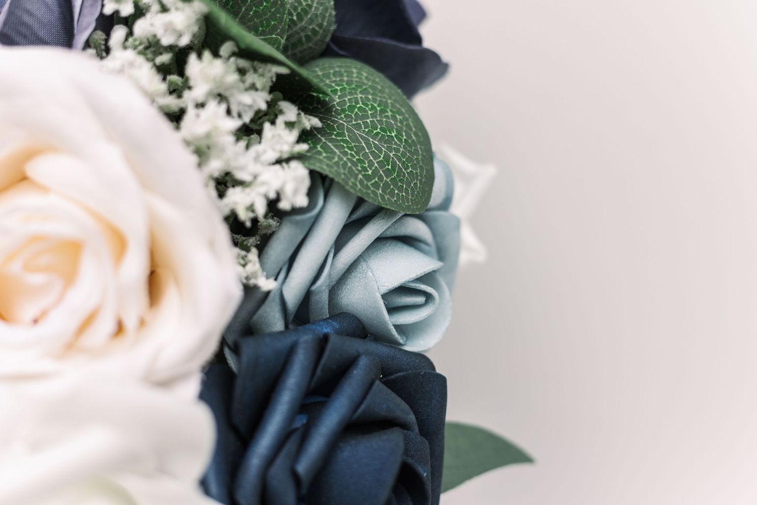 Close-up detail of a wedding bouquet with cream and navy blue roses.