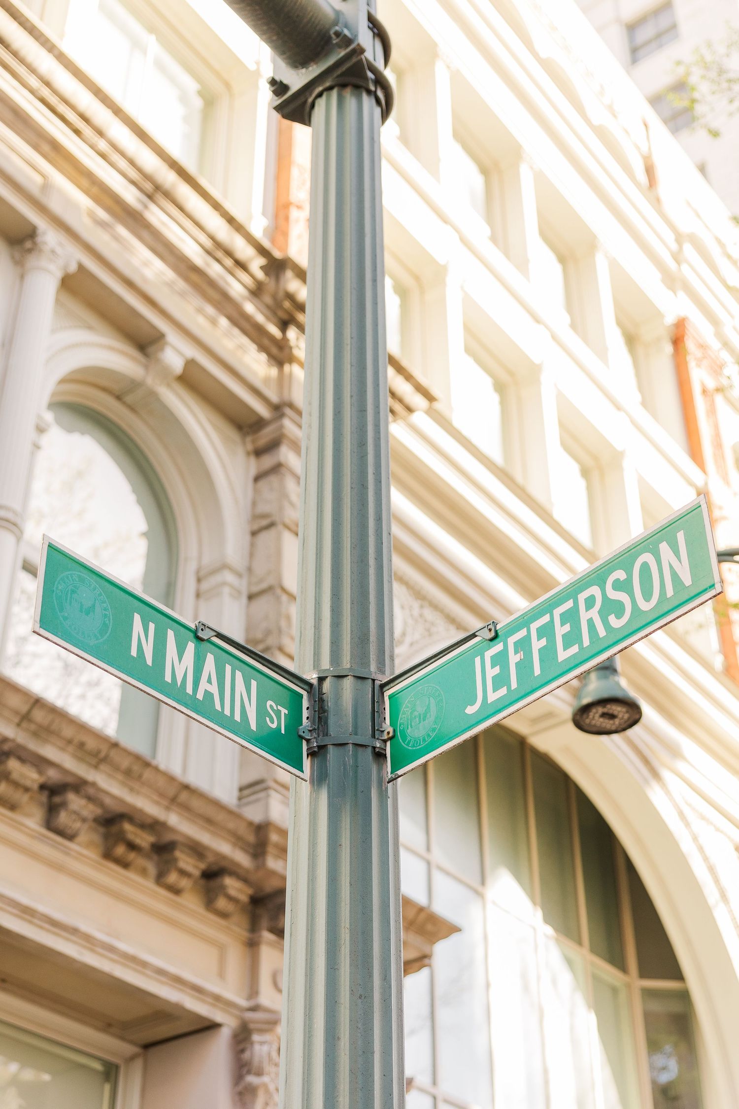 Street sign showing the intersection of N Main St and Jefferson against a classic architectural backdrop.