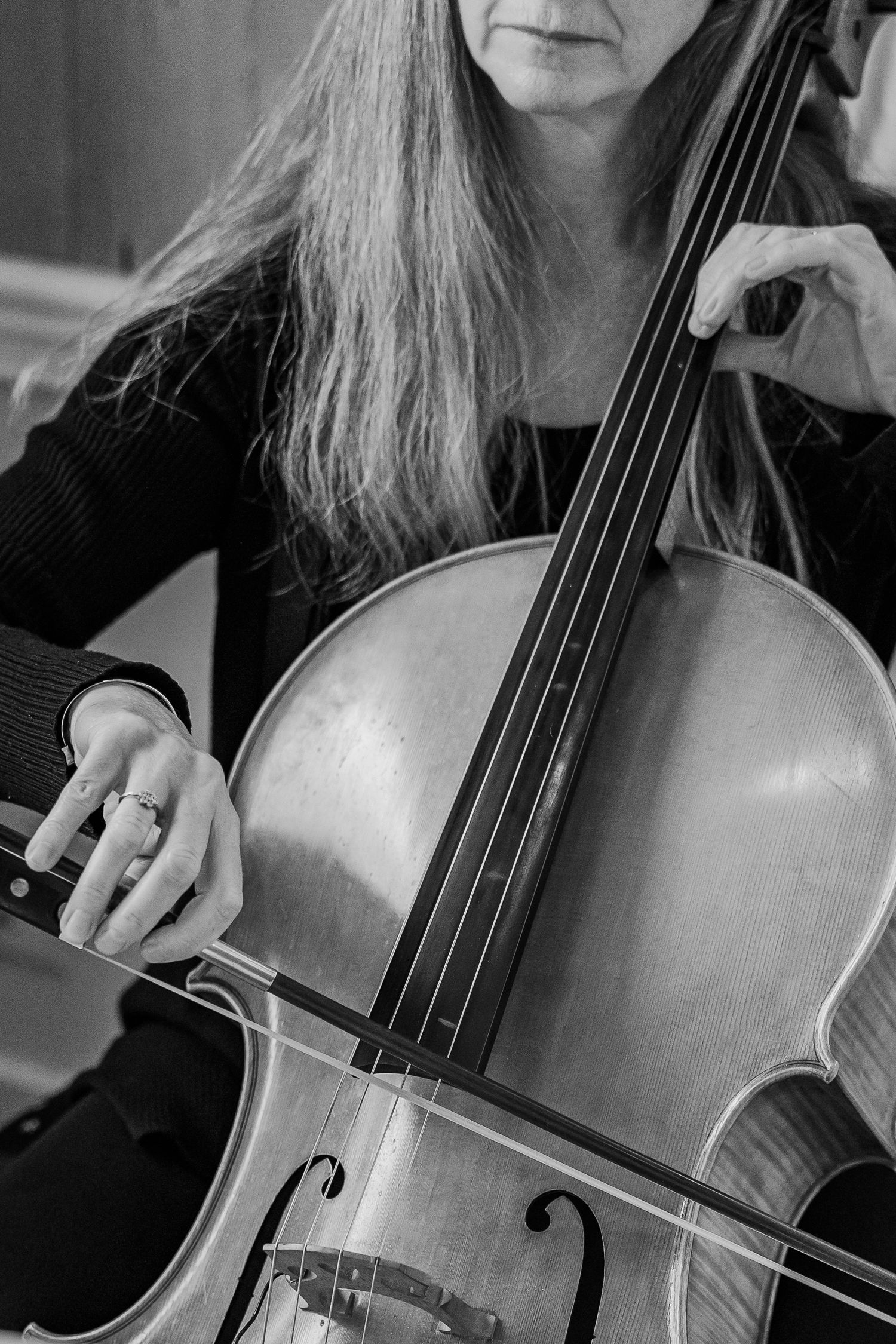 Close-up of a cellist playing their instrument in black and white.