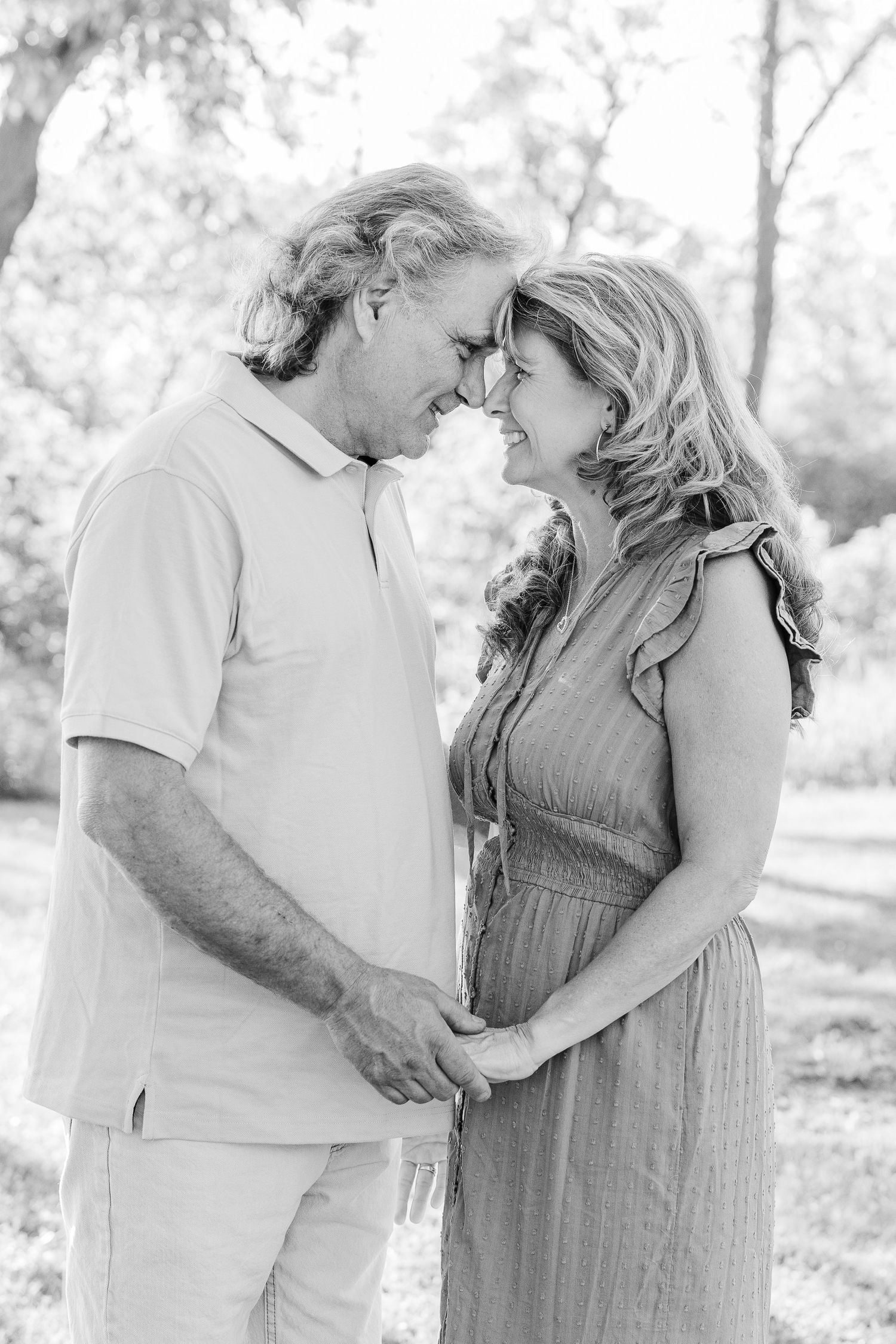An intimate black and white portrait of a couple sharing a tender moment outdoors.