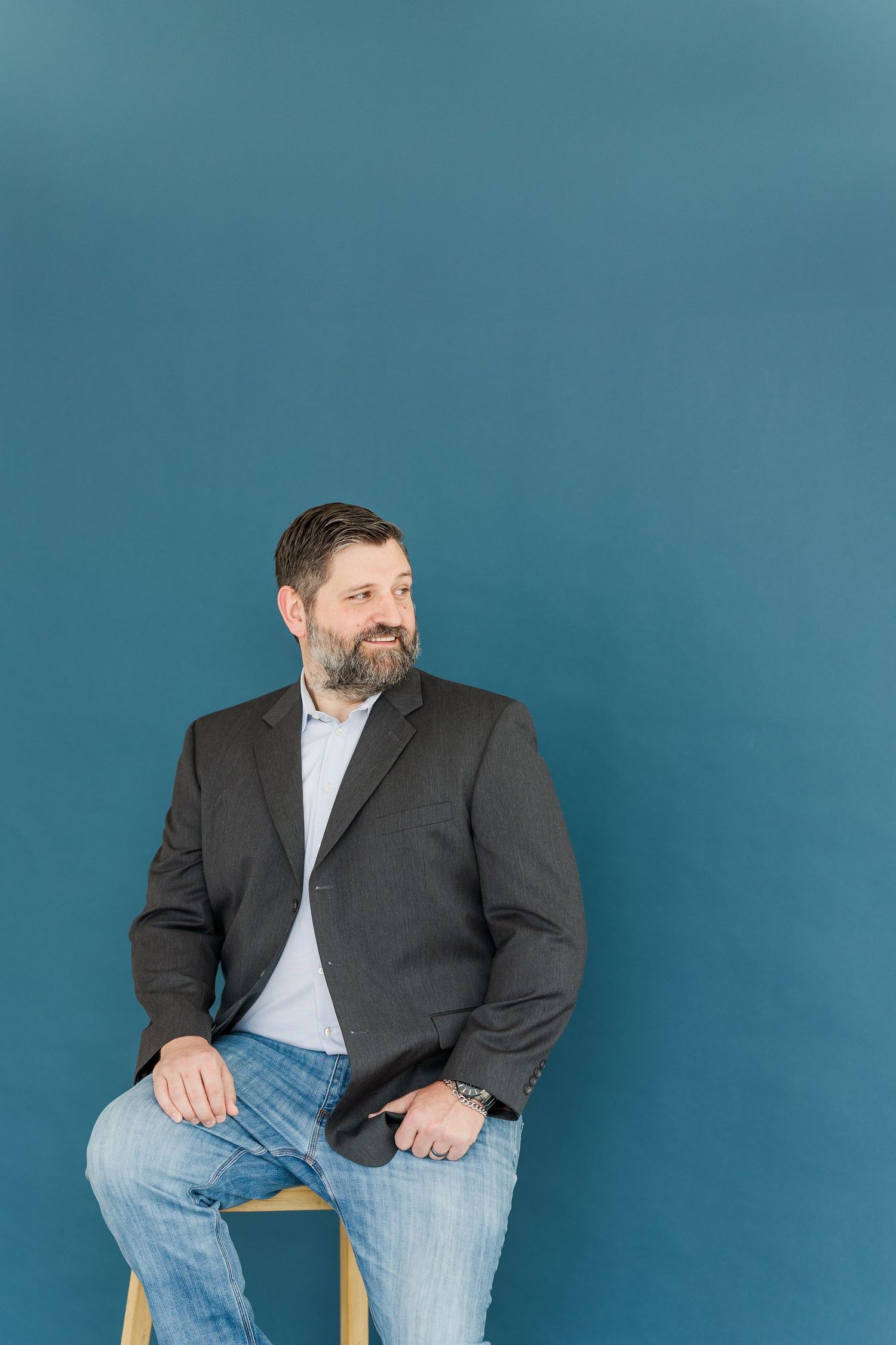 Professional headshots of person in dark suit jacket against blue background.