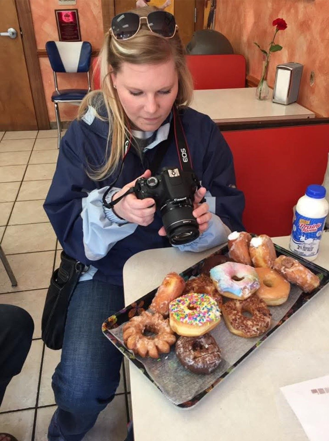Photographer capturing close-up shots of artisanal donuts on restaurant table.