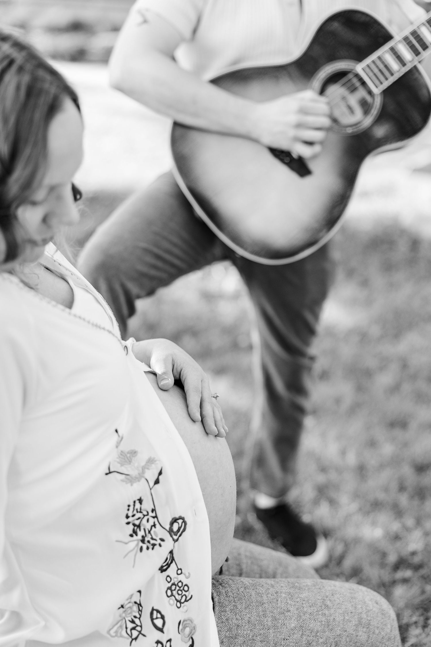 Black and white maternity photo with father playing guitar during a music-inspired Crystal Lake session at Veterans Acres Nature Center