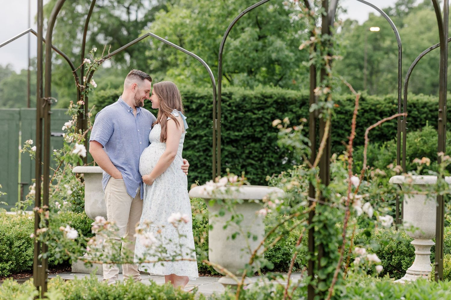 Expecting parents sharing a kiss through greenery during a Cantigny Park maternity session