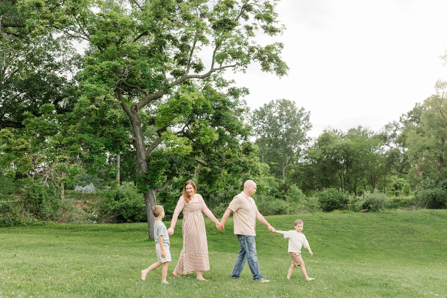 Family walking together through the park during a summer family photo session in Crystal Lake, Illinois.
