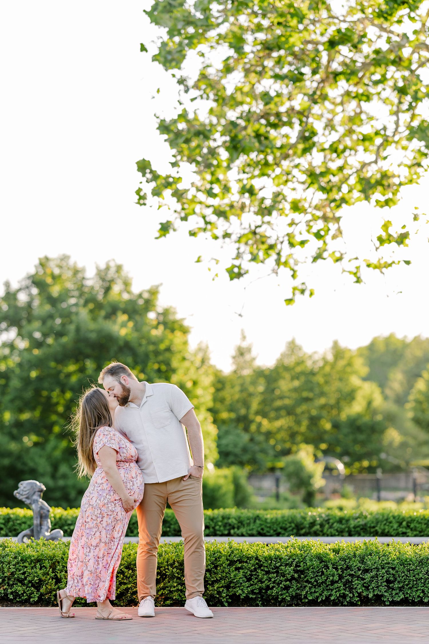 Expecting couple cuddling beneath summer trees during a Cantigny Park maternity session in Wheaton Illinois