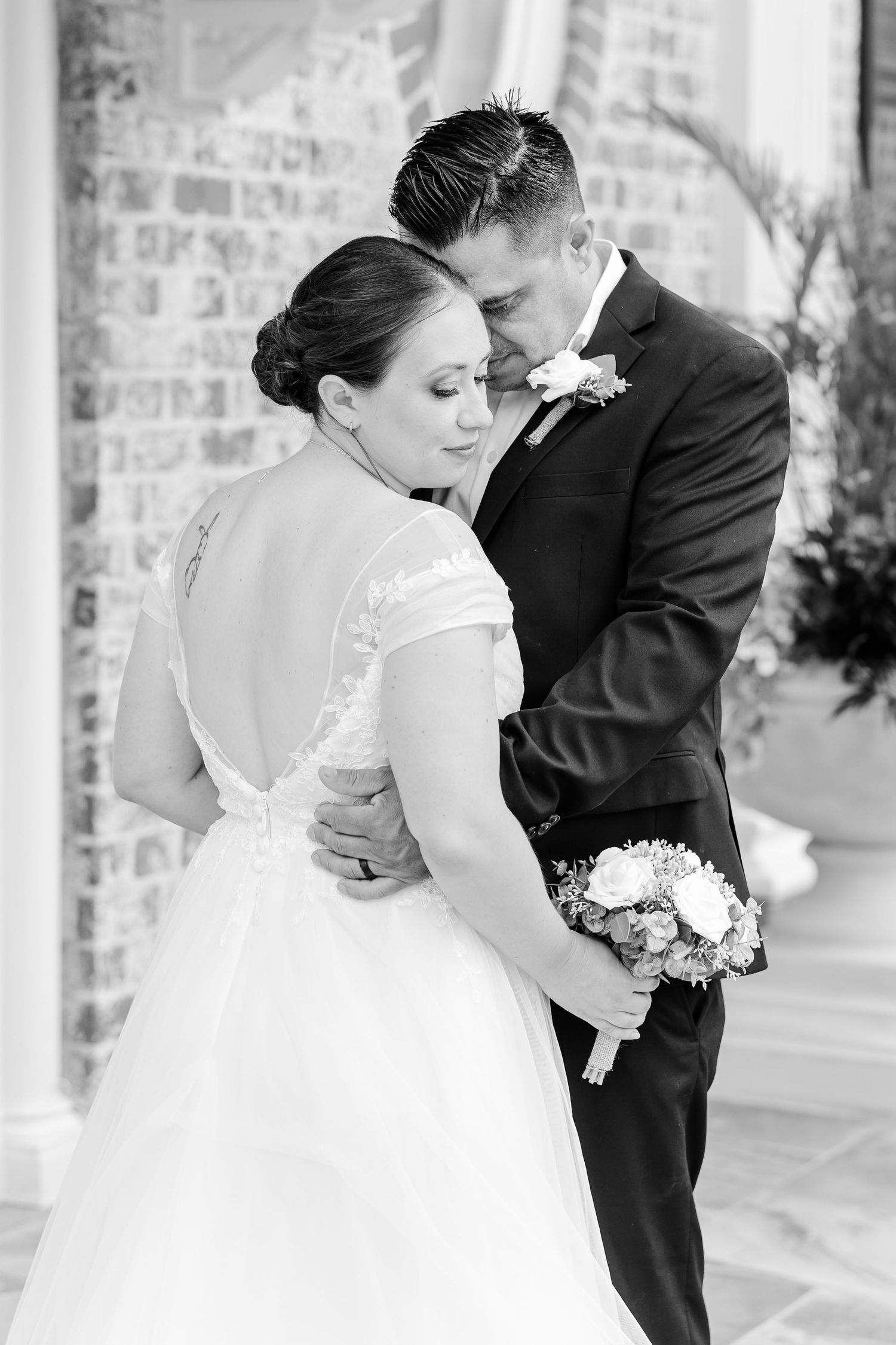 Black-and-white portrait of Rafael embracing Monika and kissing her forehead after their courthouse wedding.