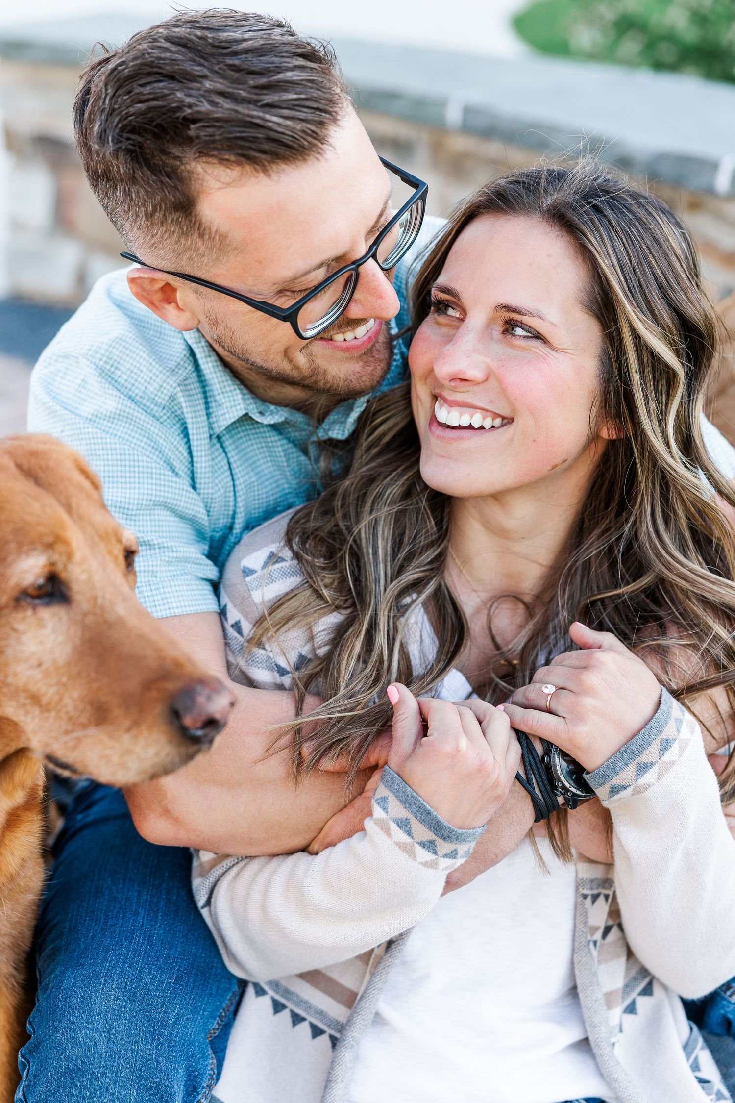 Close-up engagement portrait of a couple laughing together with their dog