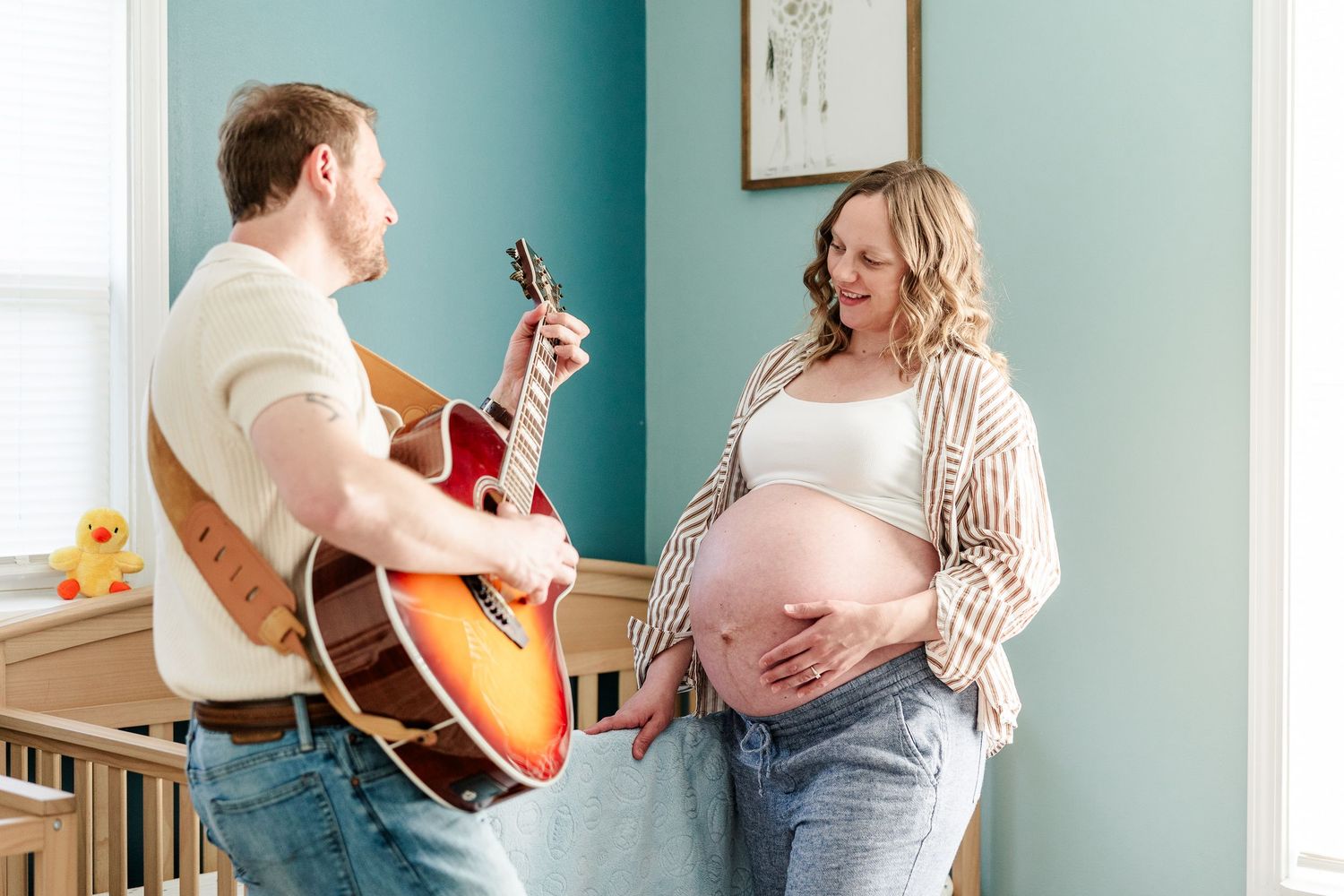 Father playing guitar for mother and babies during a music-inspired maternity session in Crystal Lake.