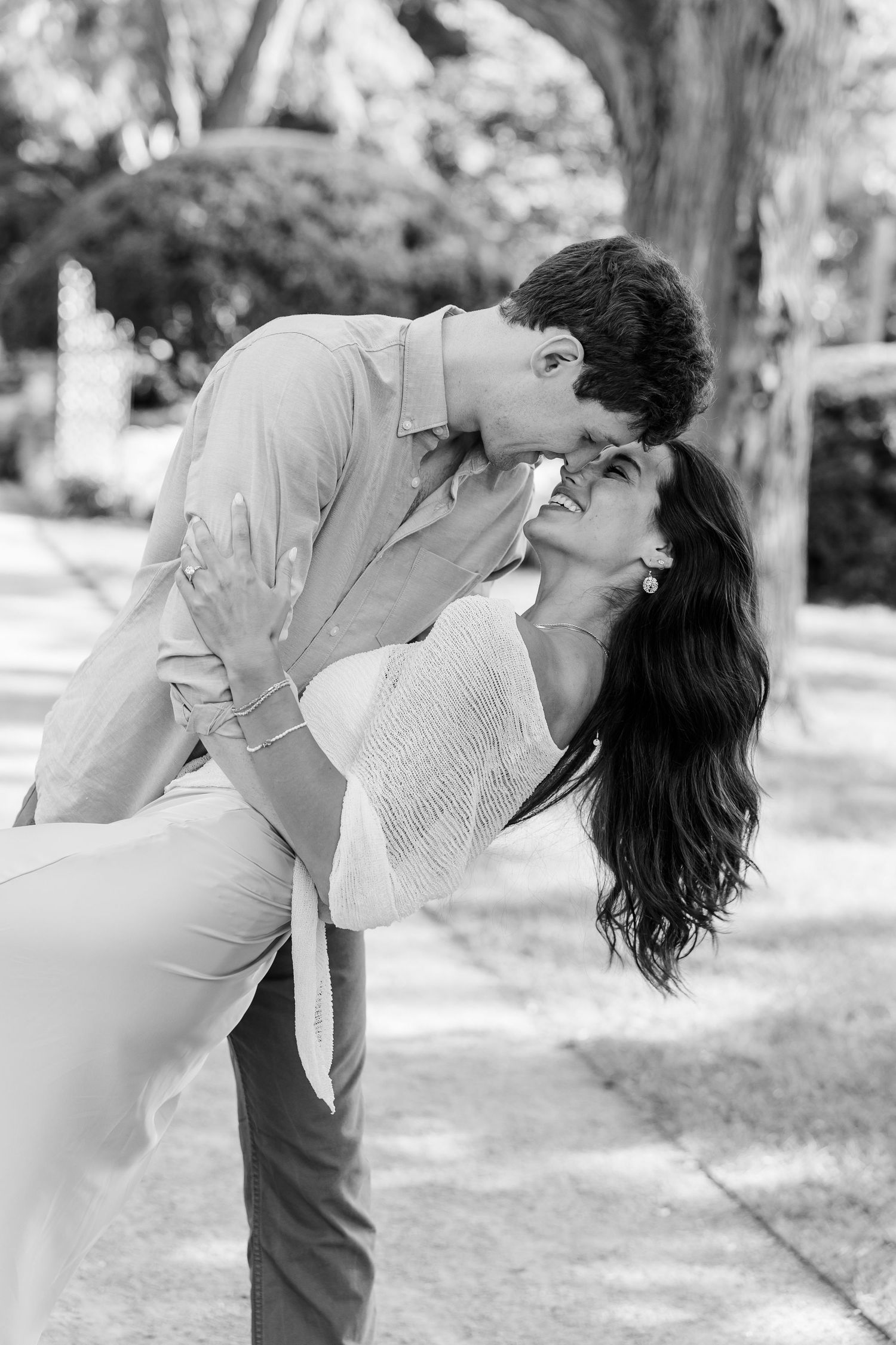Black-and-white portrait of Jack dipping Alysia for a kiss after their proposal.