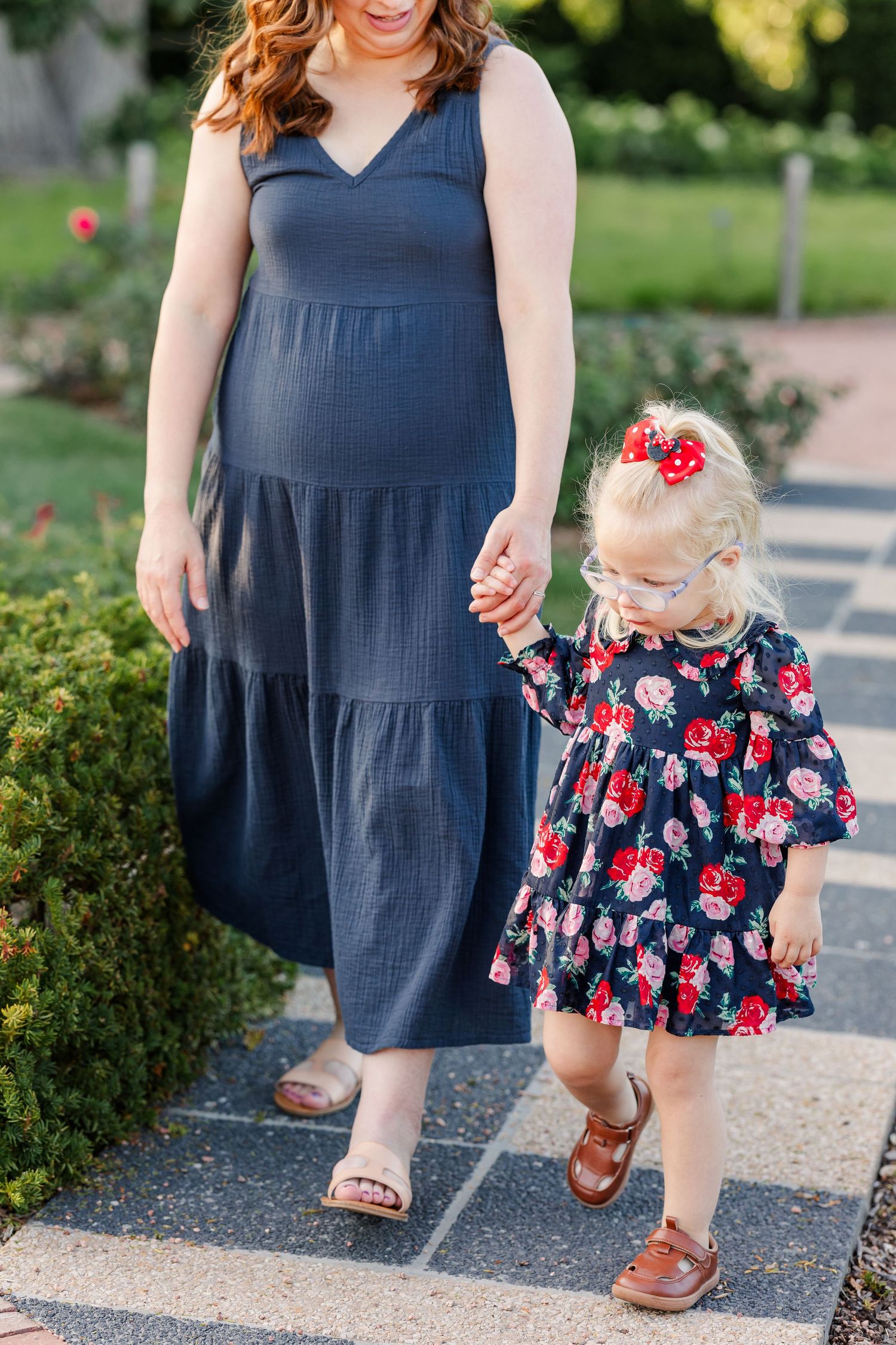 Hilary and Caroline holding hands as they walk together through the summer gardens.