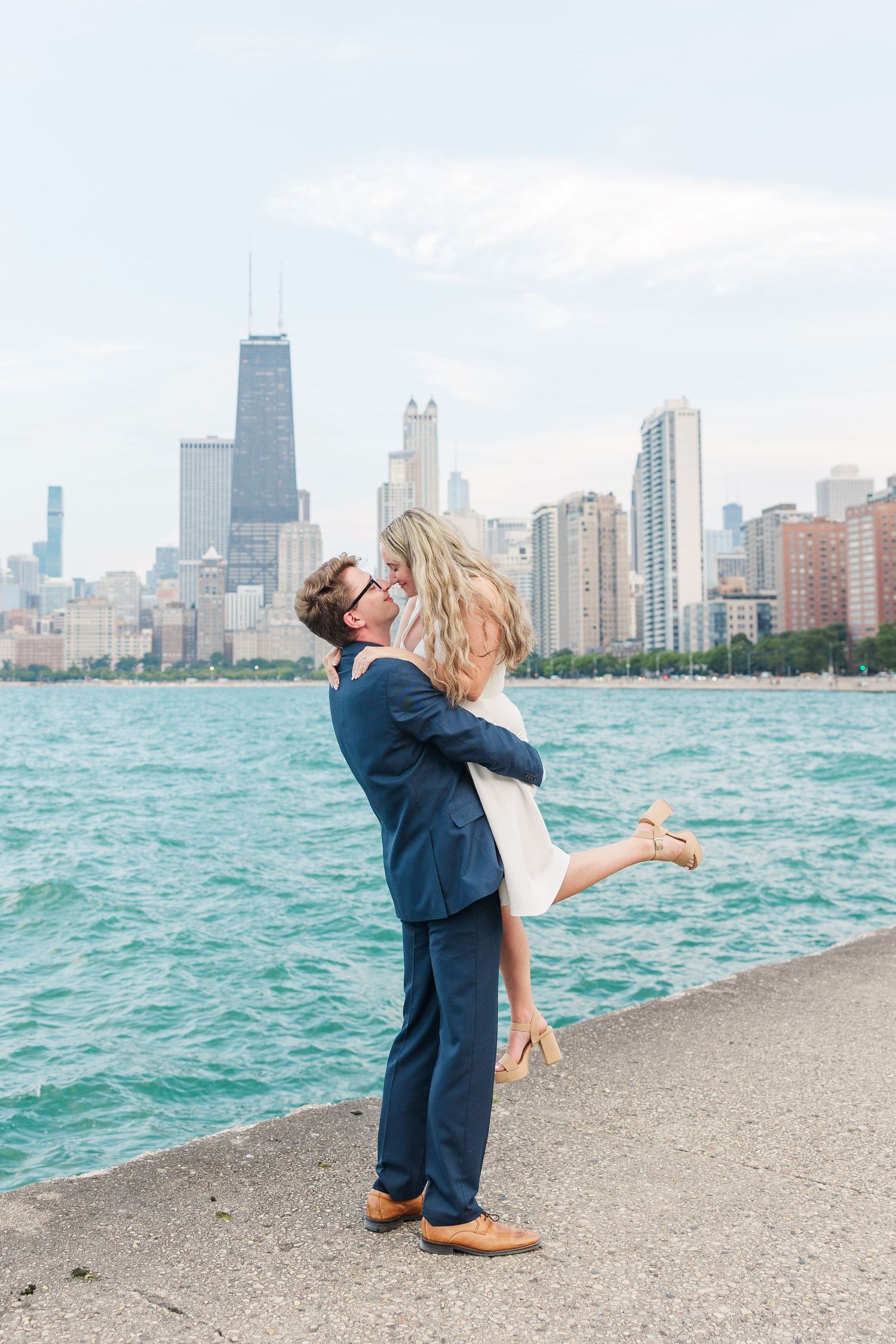 Elizabeth and Joe doing a lift with the Chicago skyline in the background at North Avenue Beach during sunset