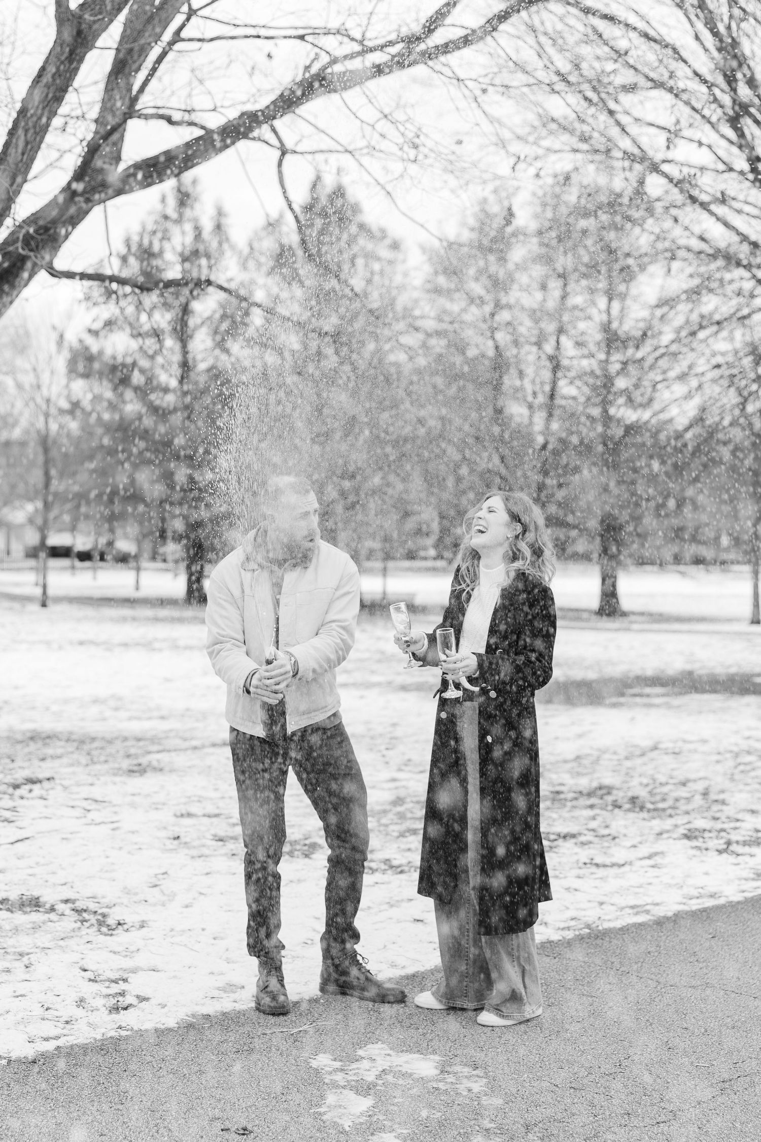a couple pops champagne in Winnemac Park to celebrate their engagement in Winter