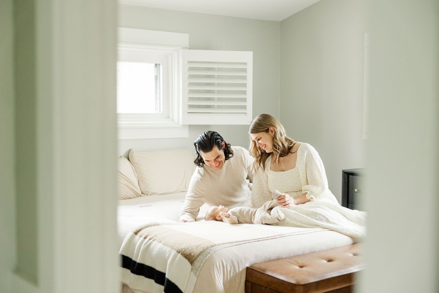 Parents smiling at their newborn baby on the bed during an in-home lifestyle newborn session in Palatine Illinois