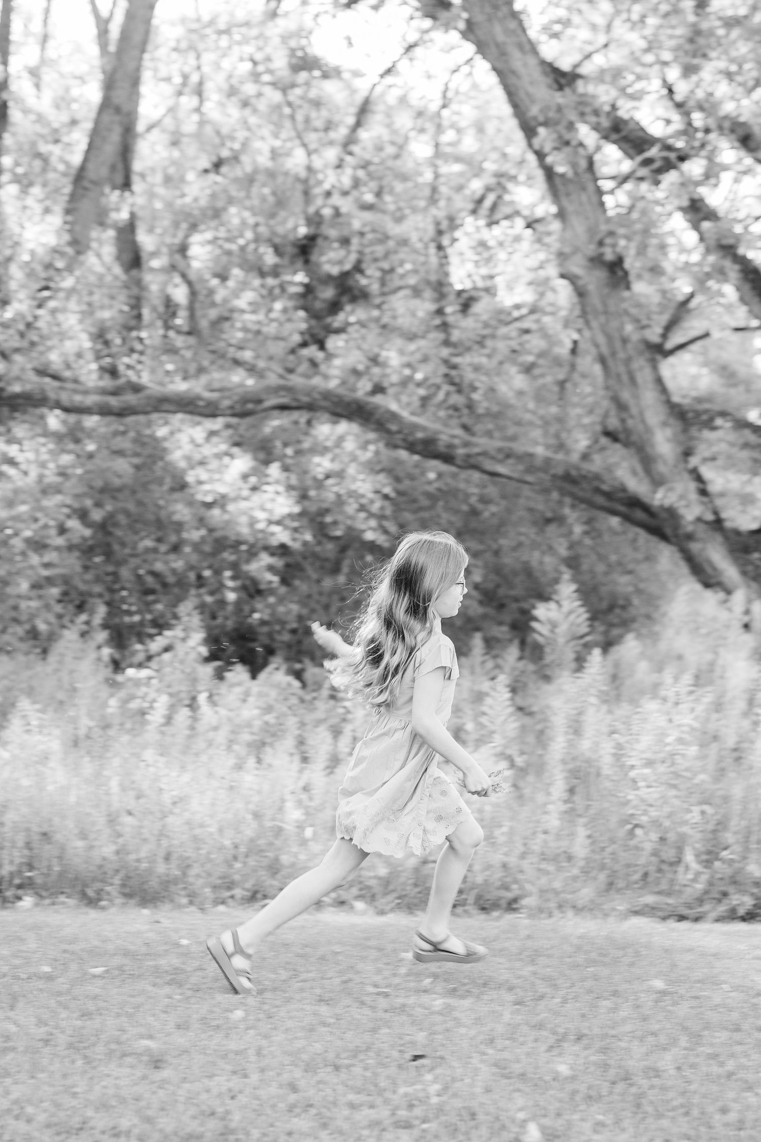 A sequence of black and white photos shows a person running and leaping through a grassy outdoor area with trees.