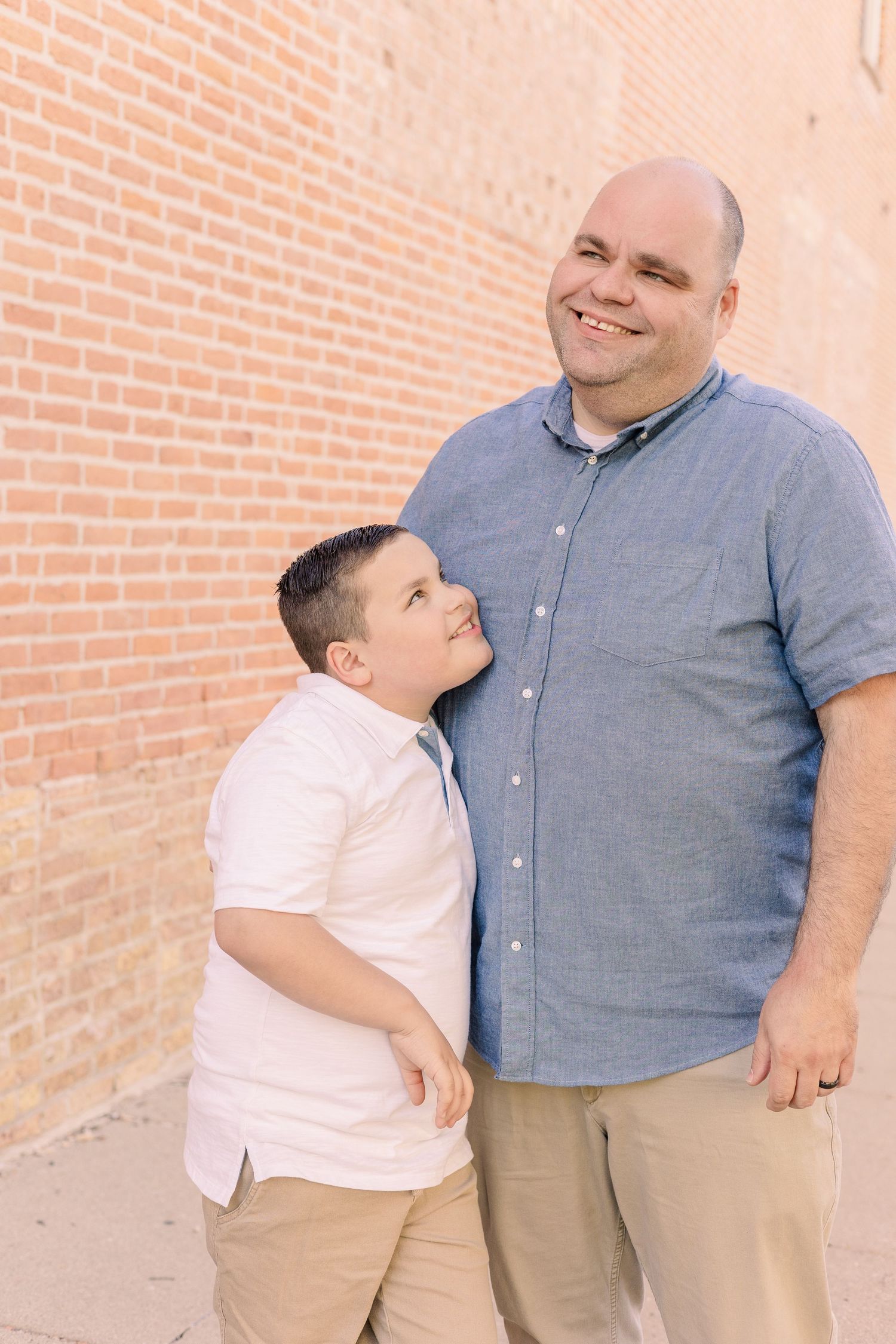 A joyful candid moment captured between two people against an orange brick wall.