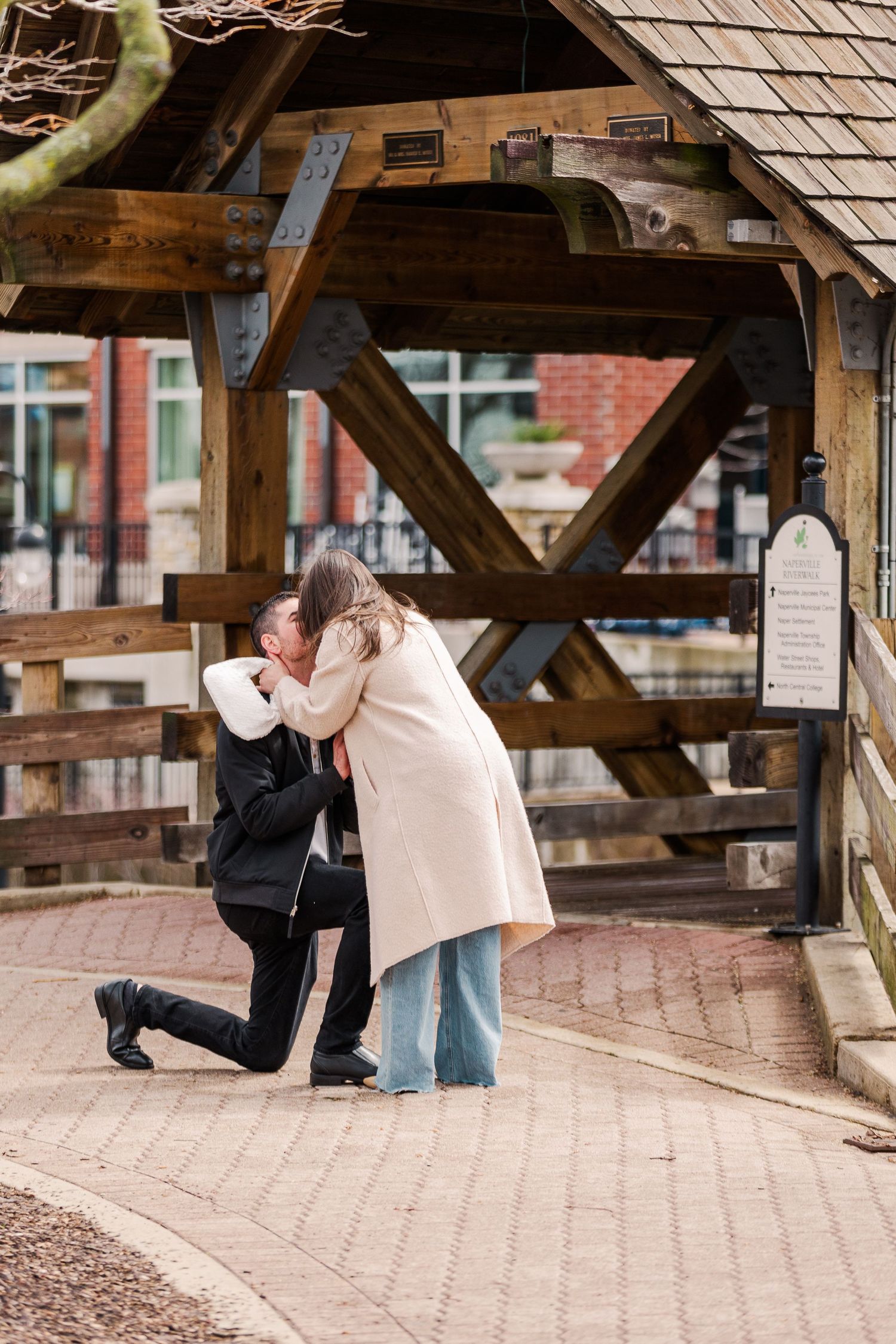 A romantic proposal moment captured under a rustic wooden structure.
