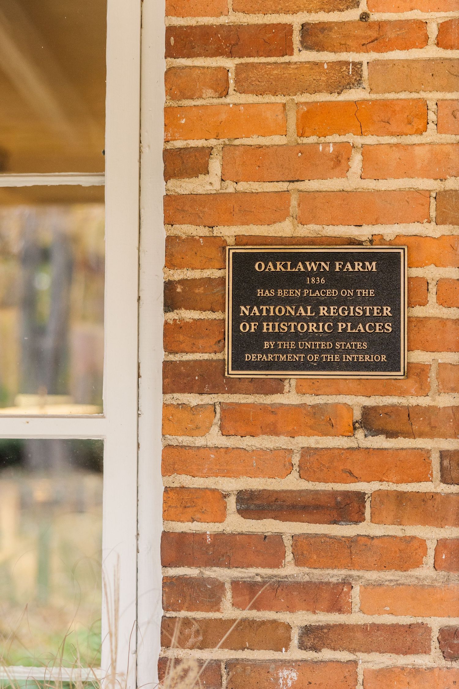 Historic plaque for Oaklawn Farm mounted on red brick wall.