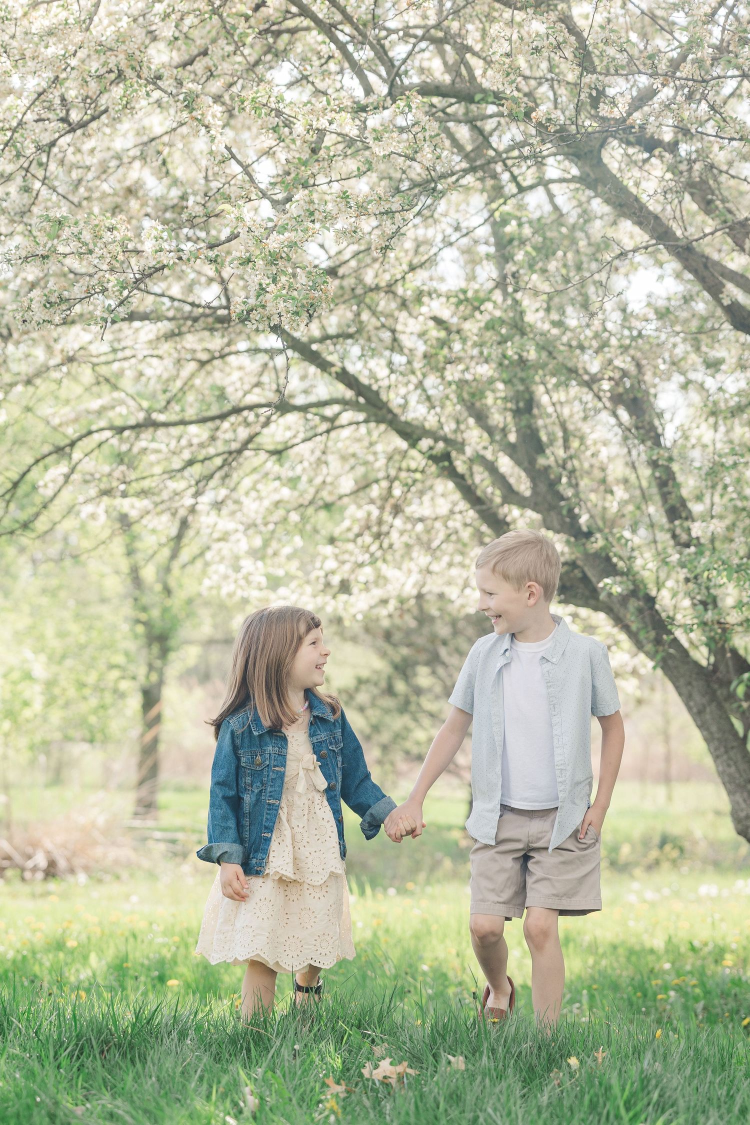 Two children share a sweet moment under blooming spring cherry trees.