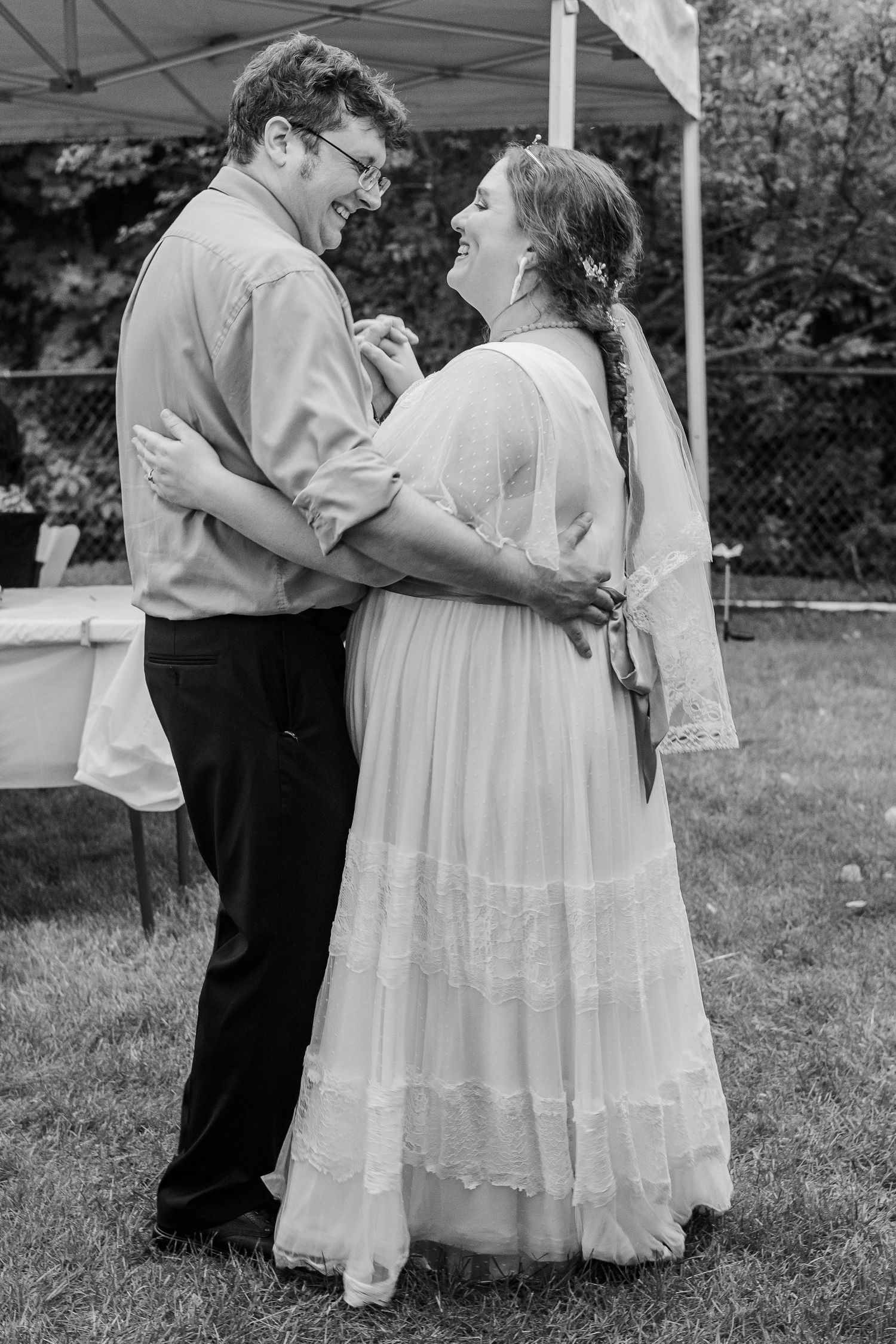 A couple shares a tender dance moment at their backyard wedding reception.