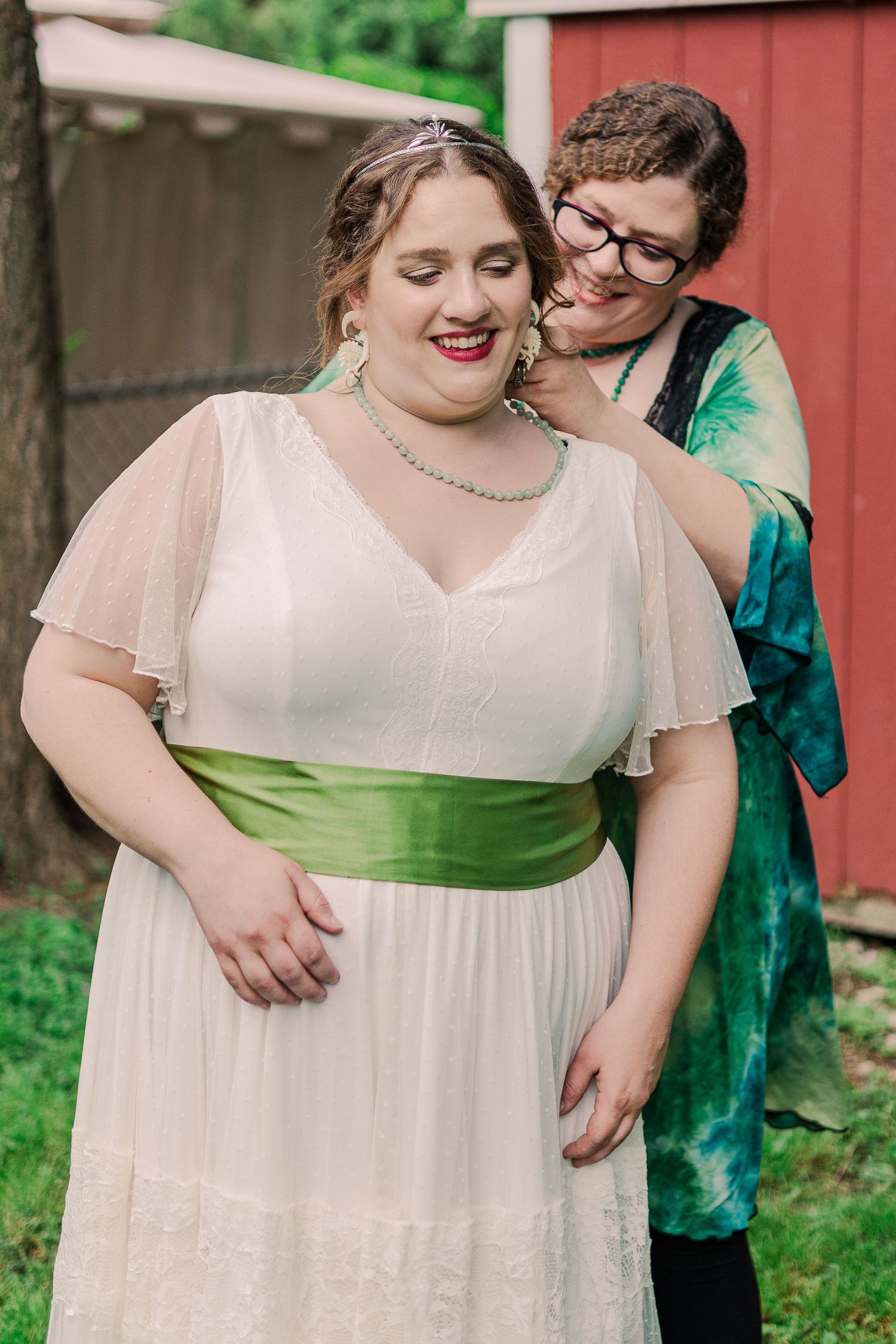 Two people share intimate moment in formal attire against red barn backdrop.