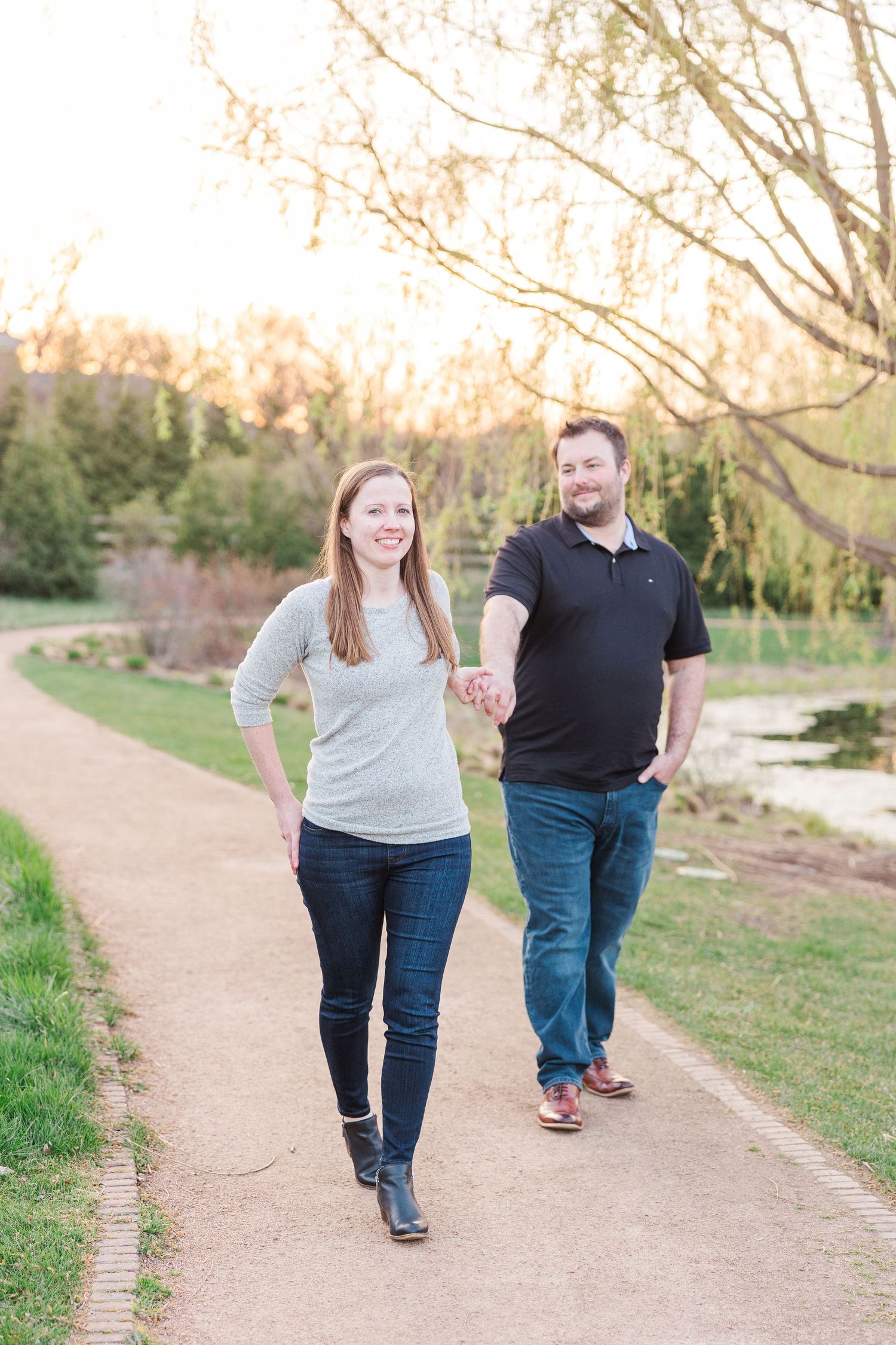 Couple walking together on garden path during sunset while holding hands.