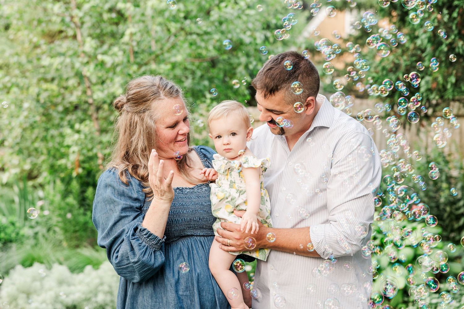 Sweet family portrait captured in a lush summer garden setting.