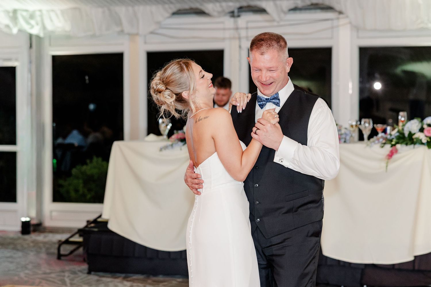 Bride and groom smiling during their first dance inside an elegant wedding reception venue.