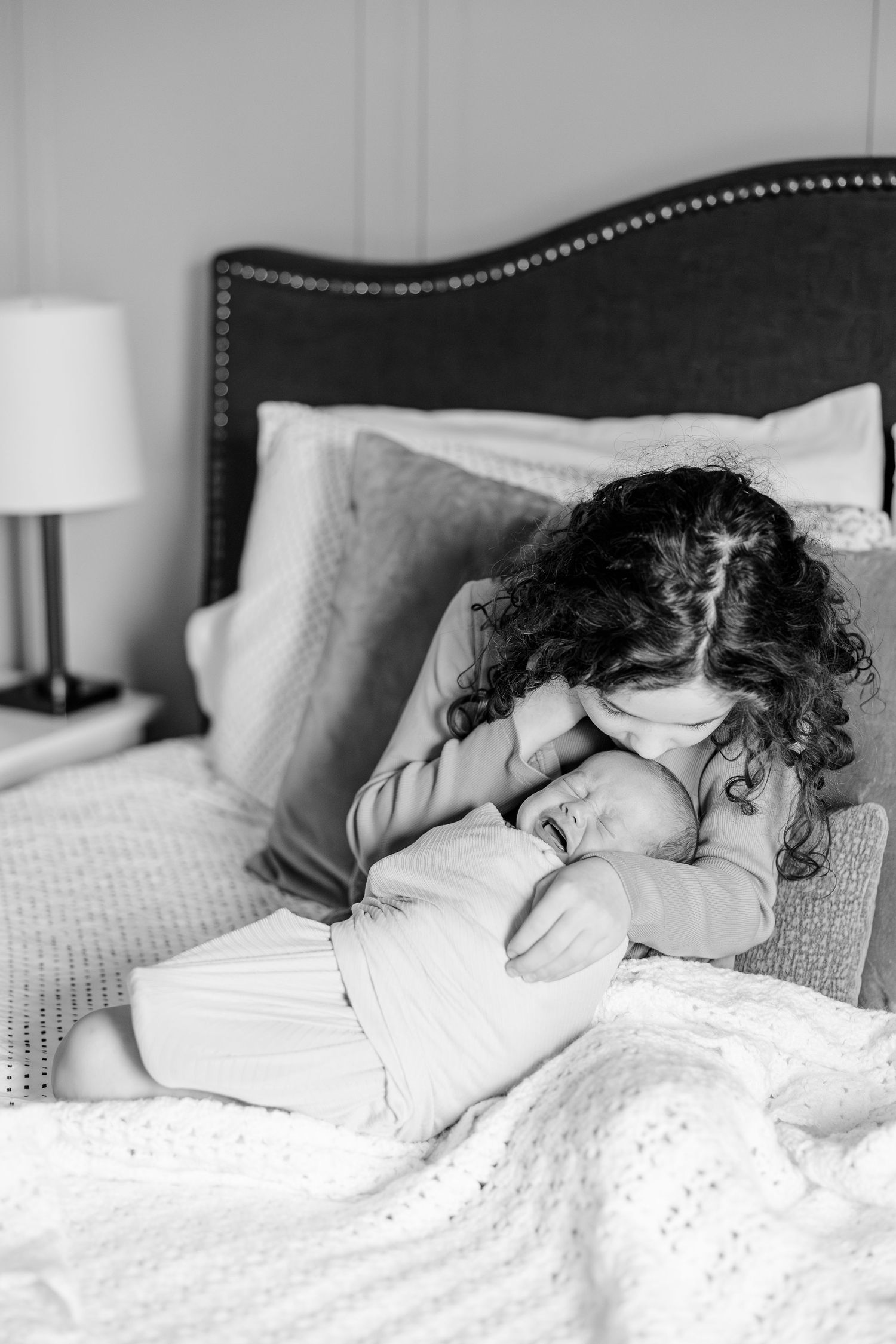 Black and white portrait of big sister holding newborn during Crystal Lake lifestyle newborn session