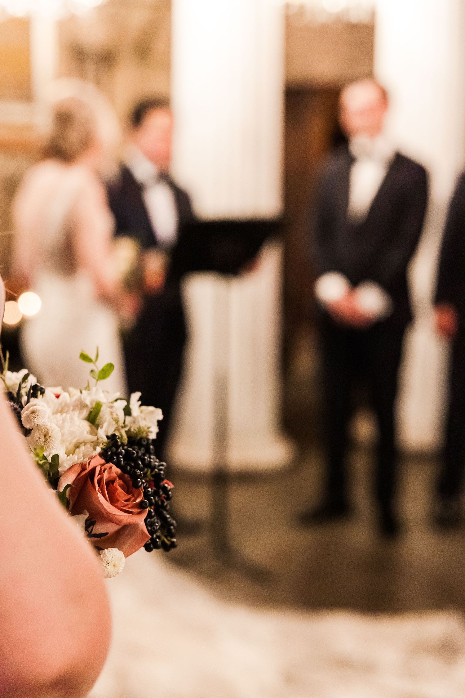 Close-up of a bridal bouquet with roses and white flowers during ceremony.