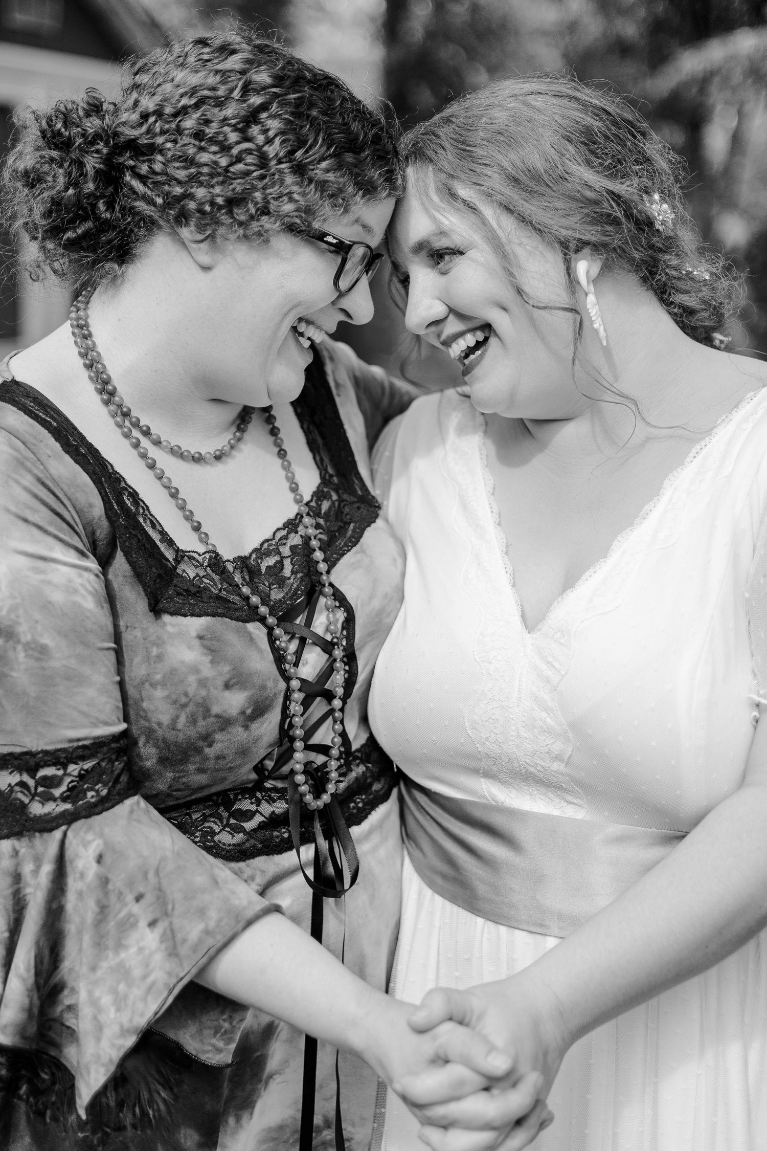 Two people share an intimate laughing moment at a wedding celebration.