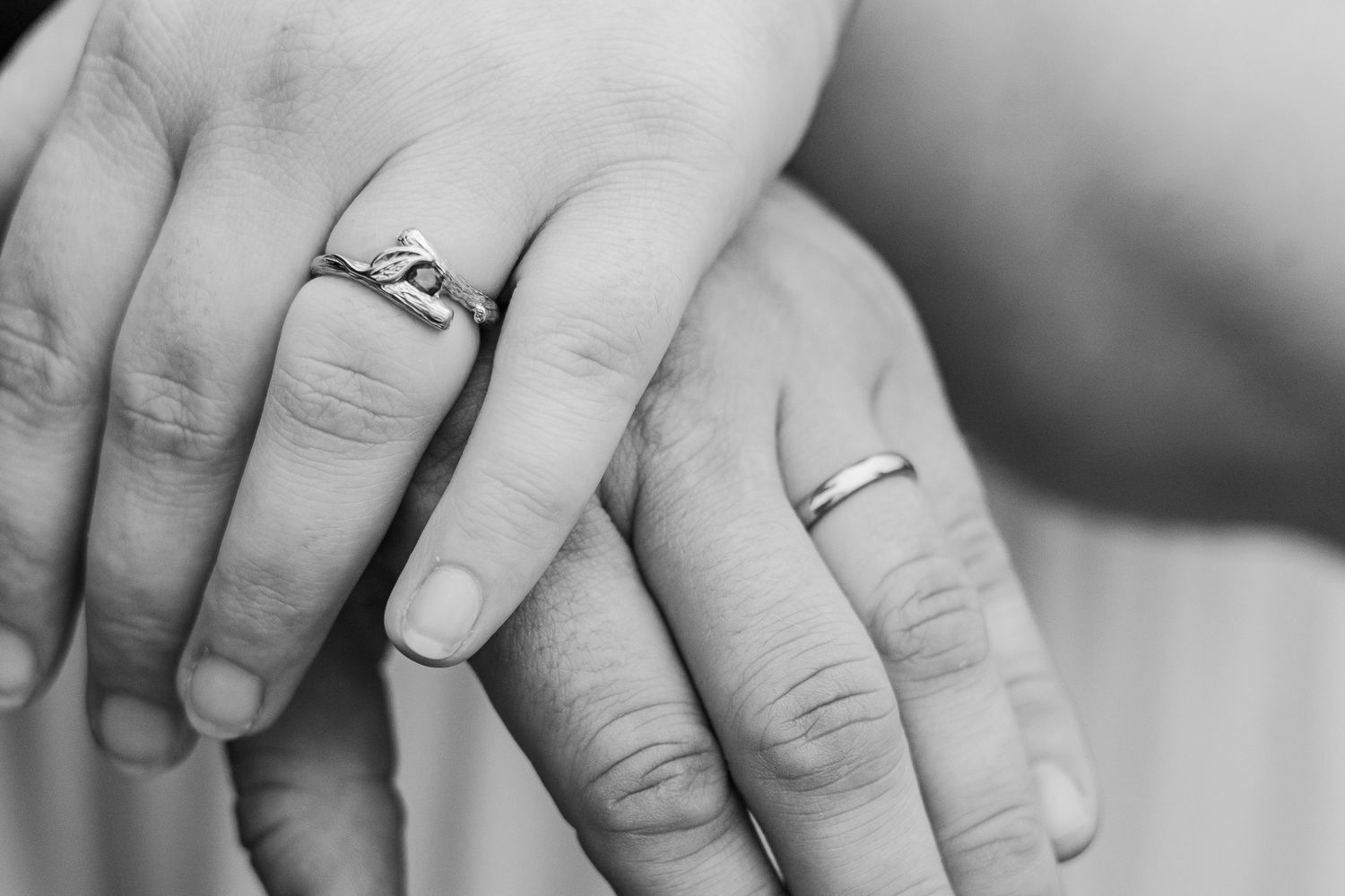 Black and white close-up of newlywed couples' hands showing their wedding rings.