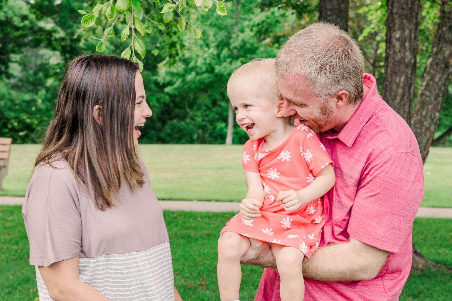 A family shares a joyful moment together outdoors in a park setting.
