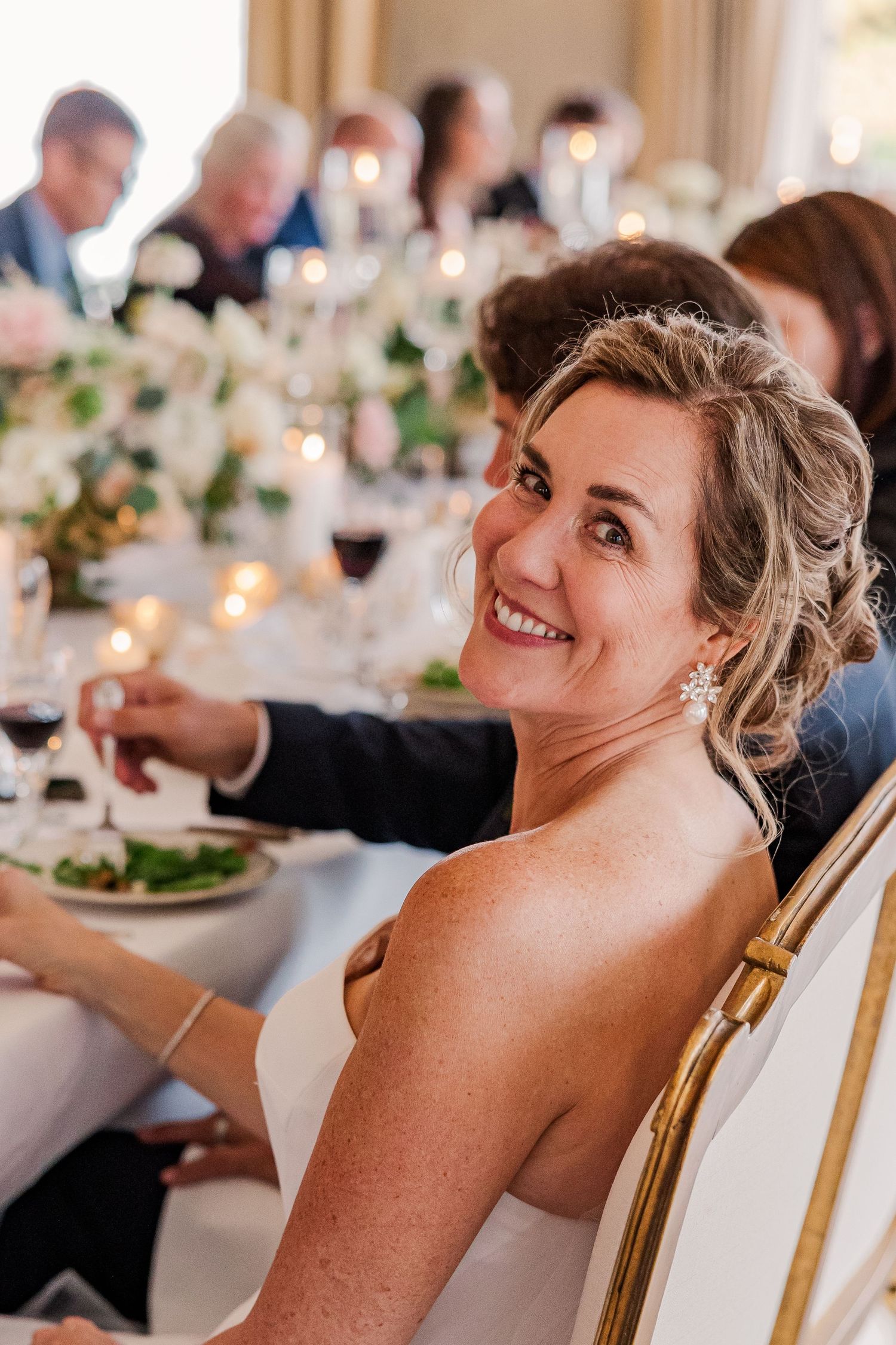 A guest enjoying dinner at an elegant wedding reception with table settings and floral centerpieces.
