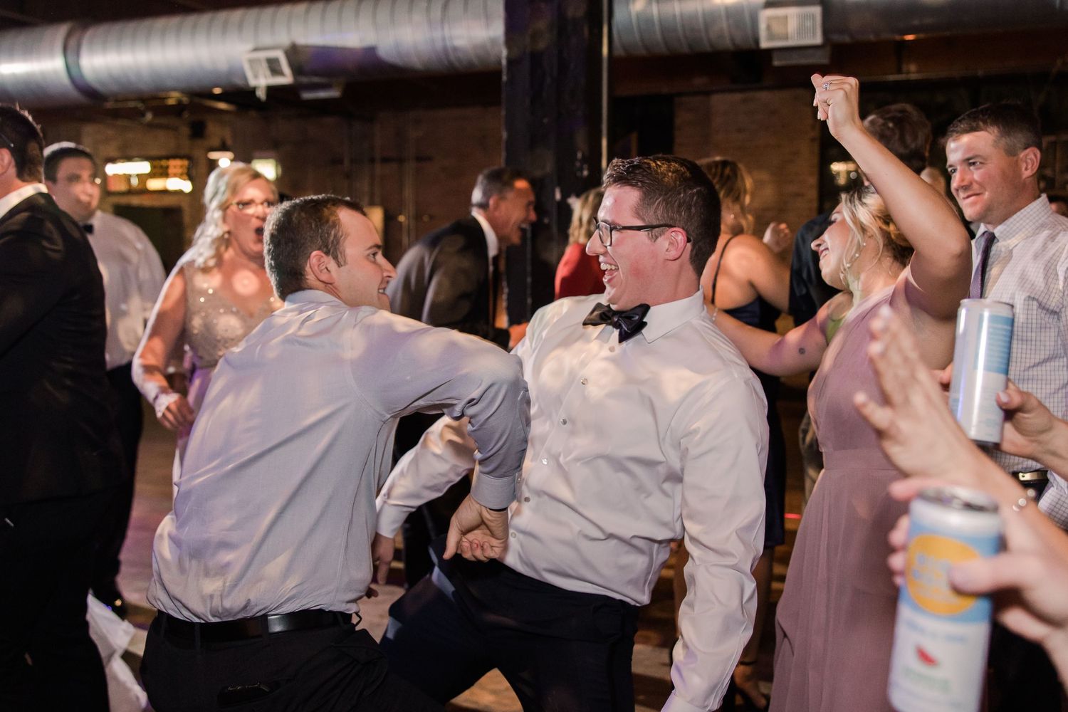 Party guests dancing and celebrating in a dimly lit industrial event space.