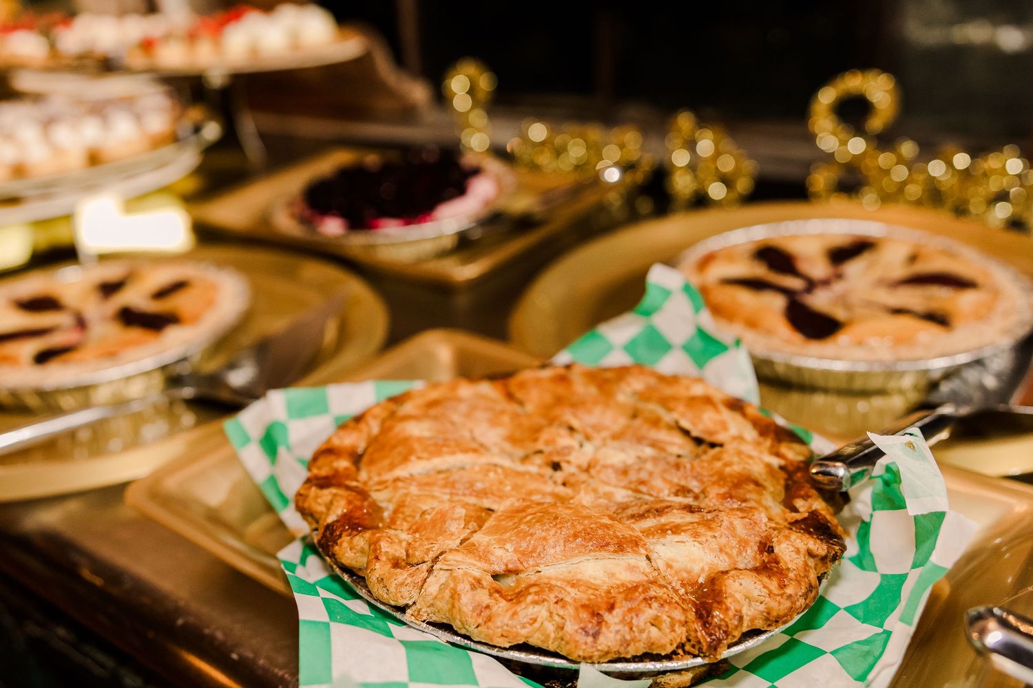 Fresh baked pies on display with decorative gold accents at wedding dessert table.