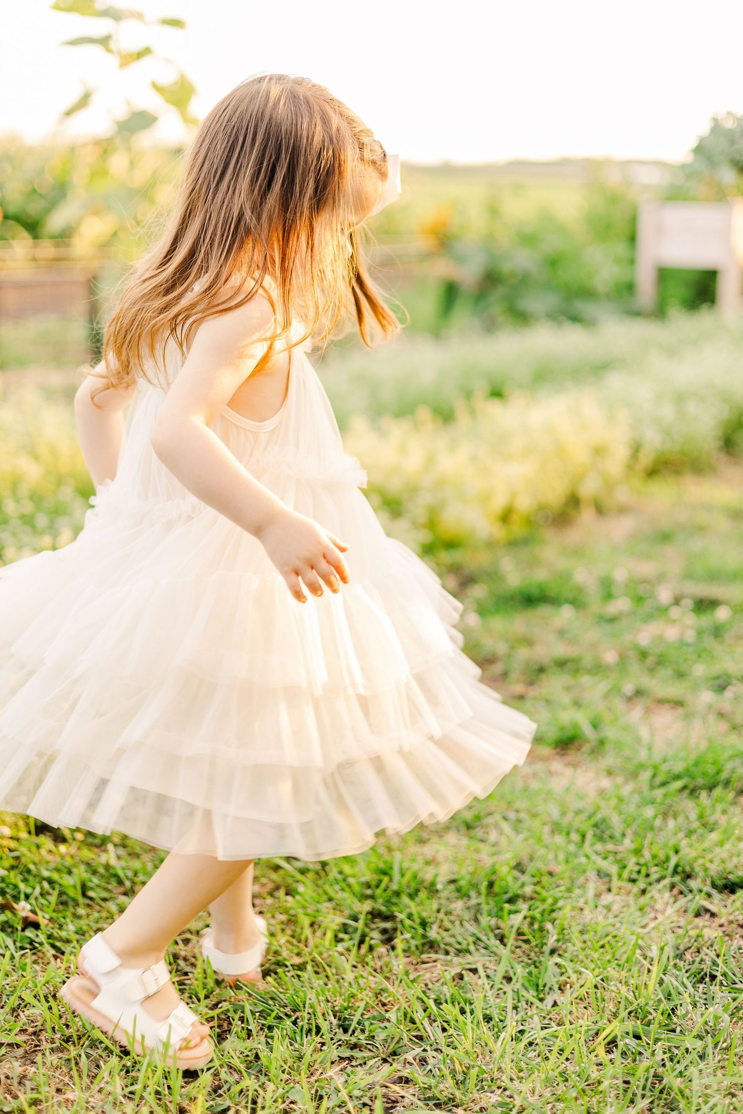 A carefree summer dance in a white ruffled dress among garden wildflowers.