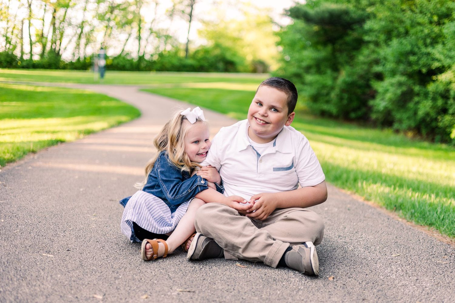 Two people share a joyful moment while sitting on a curved park path.