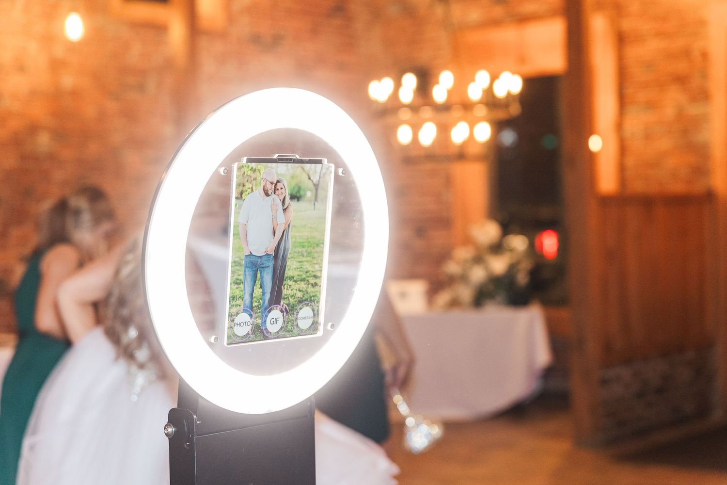 Ring light photo setup at a wedding reception with exposed brick walls and ambient lighting.