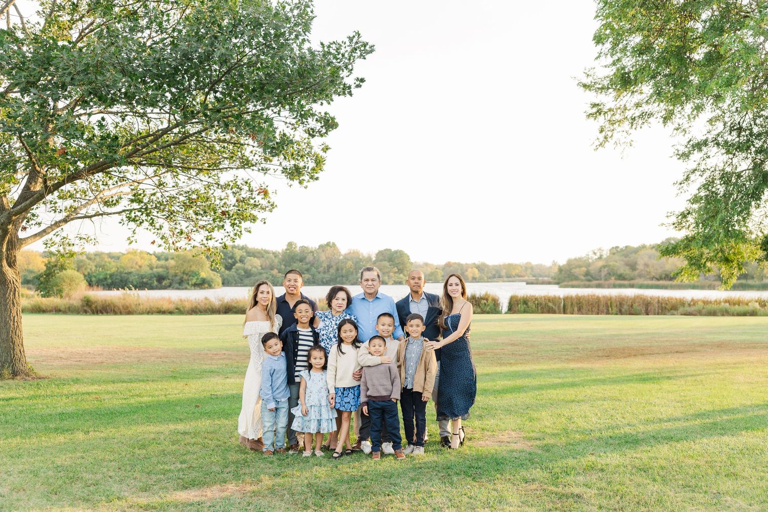 A group gathers on a grassy hillside during golden hour for outdoor family portraits in a rural setting. Busse Woods