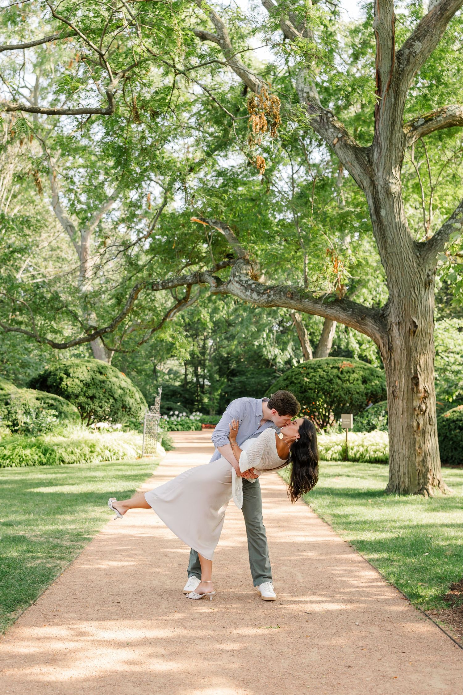 Alysia kicks up her heel as Jack dips and kisses her along the garden path.