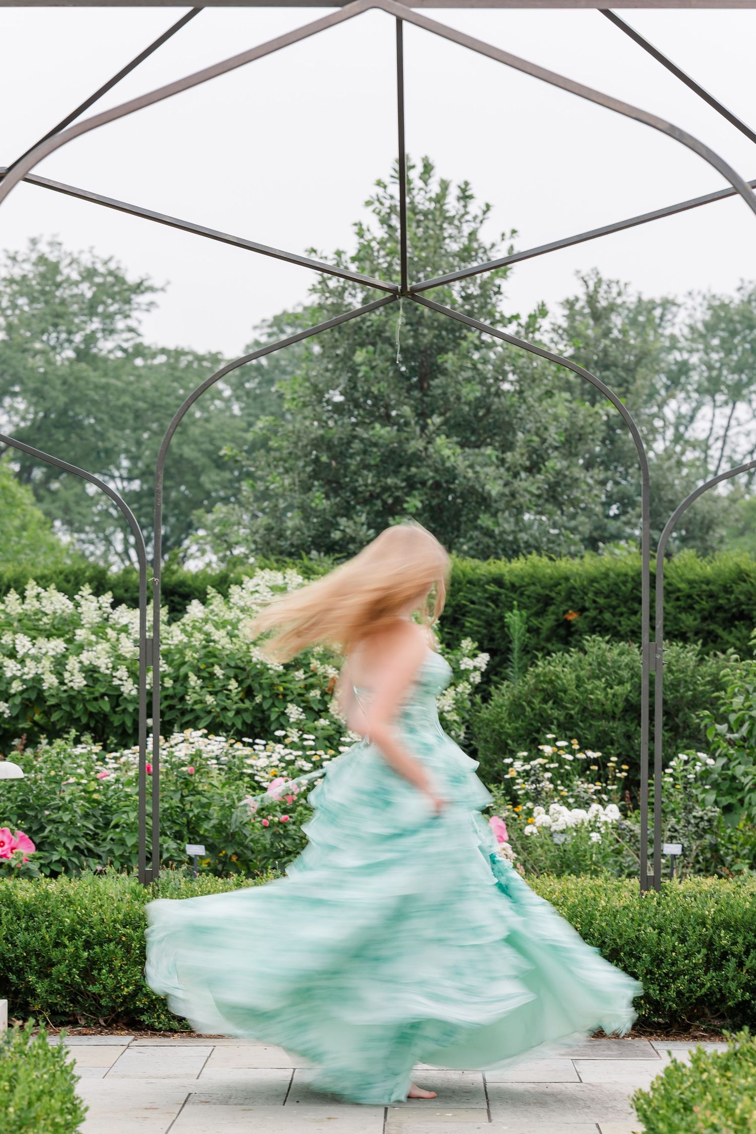 Samantha twirls in her mint floral dress beneath a garden arbor during her Cantigny Park senior portraits.
