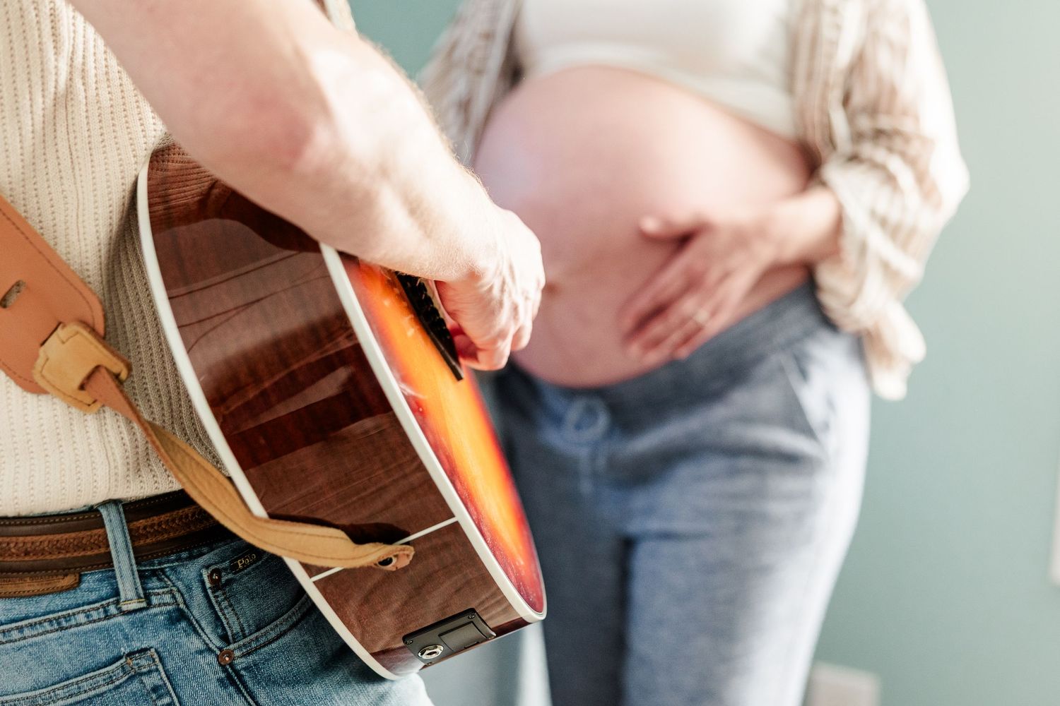 Close-up of father playing guitar beside baby bump during a music-inspired maternity session in Crystal Lake.